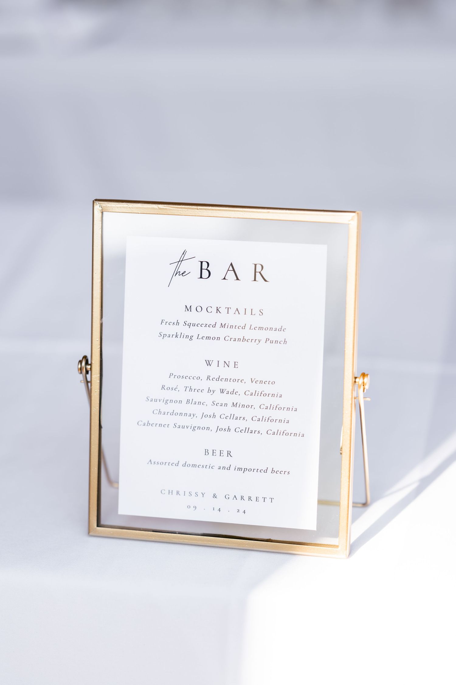 Elegant wedding bar menu cards with gold frames displaying wine and cocktail selections.