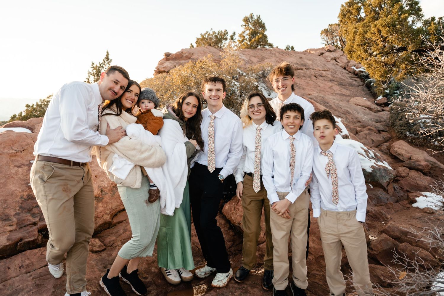 Wedding party gathered on red rocks during golden hour.
