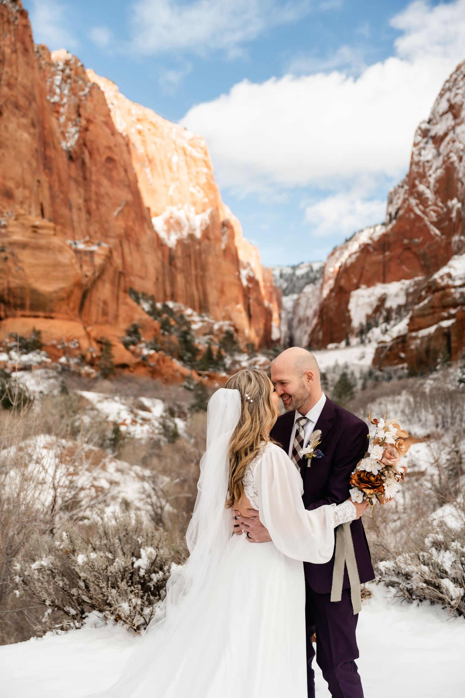 A couple shares a romantic moment in the snowy landscape of Garden of the Gods with red rock formations in winter.
