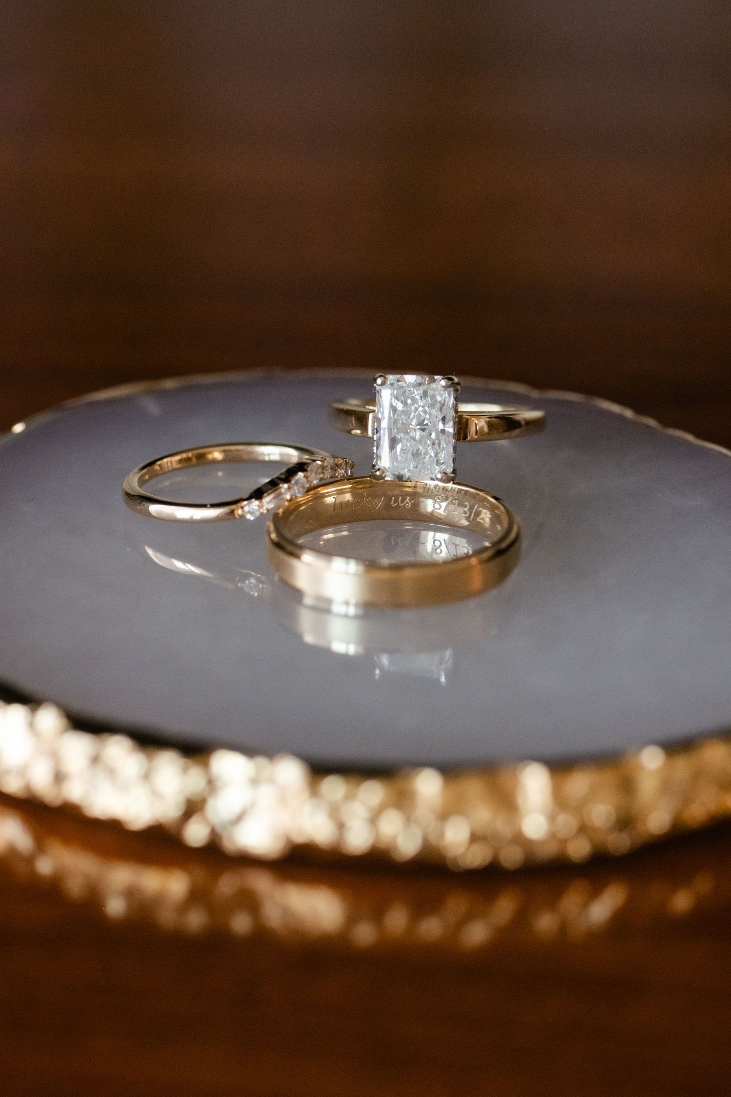 Close-up macro shot of gold wedding rings with diamonds on a reflective surface with bokeh effects.