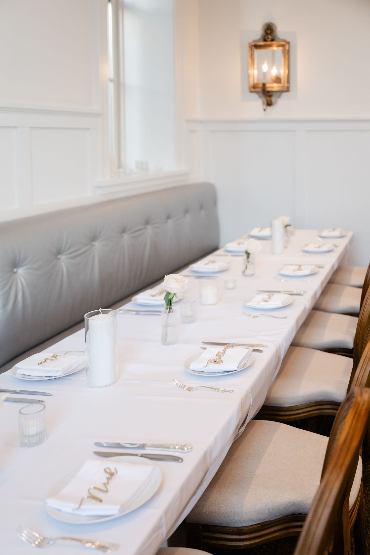 Elegant restaurant interior with grey banquette seating and white table settings.