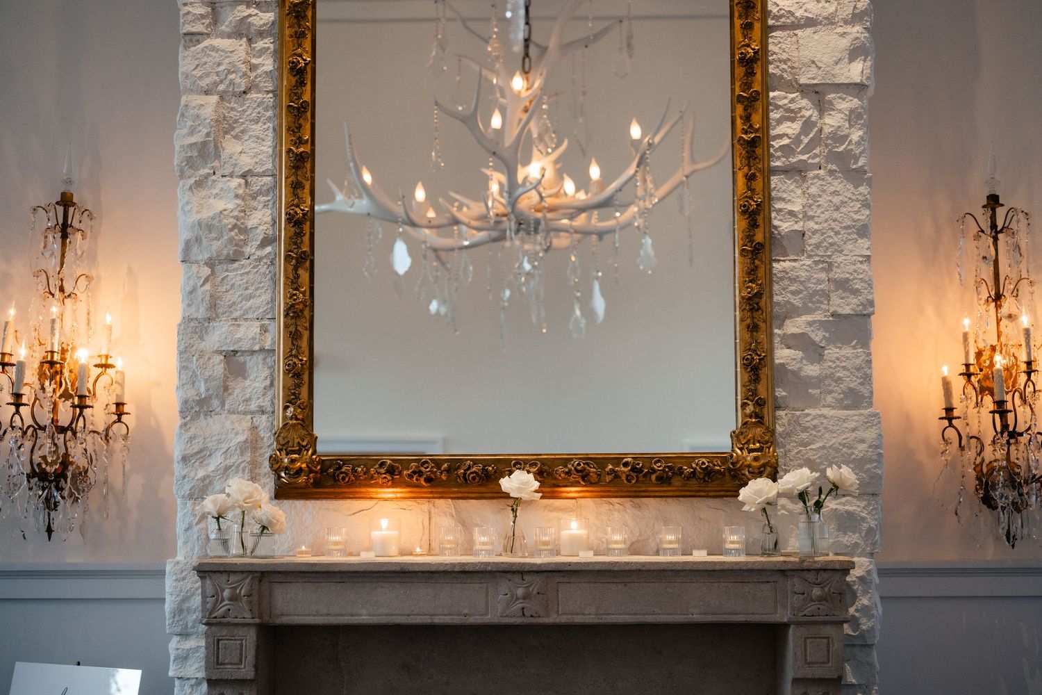 Elegant reception room features ornate gold frames and crystal chandeliers on marble walls.