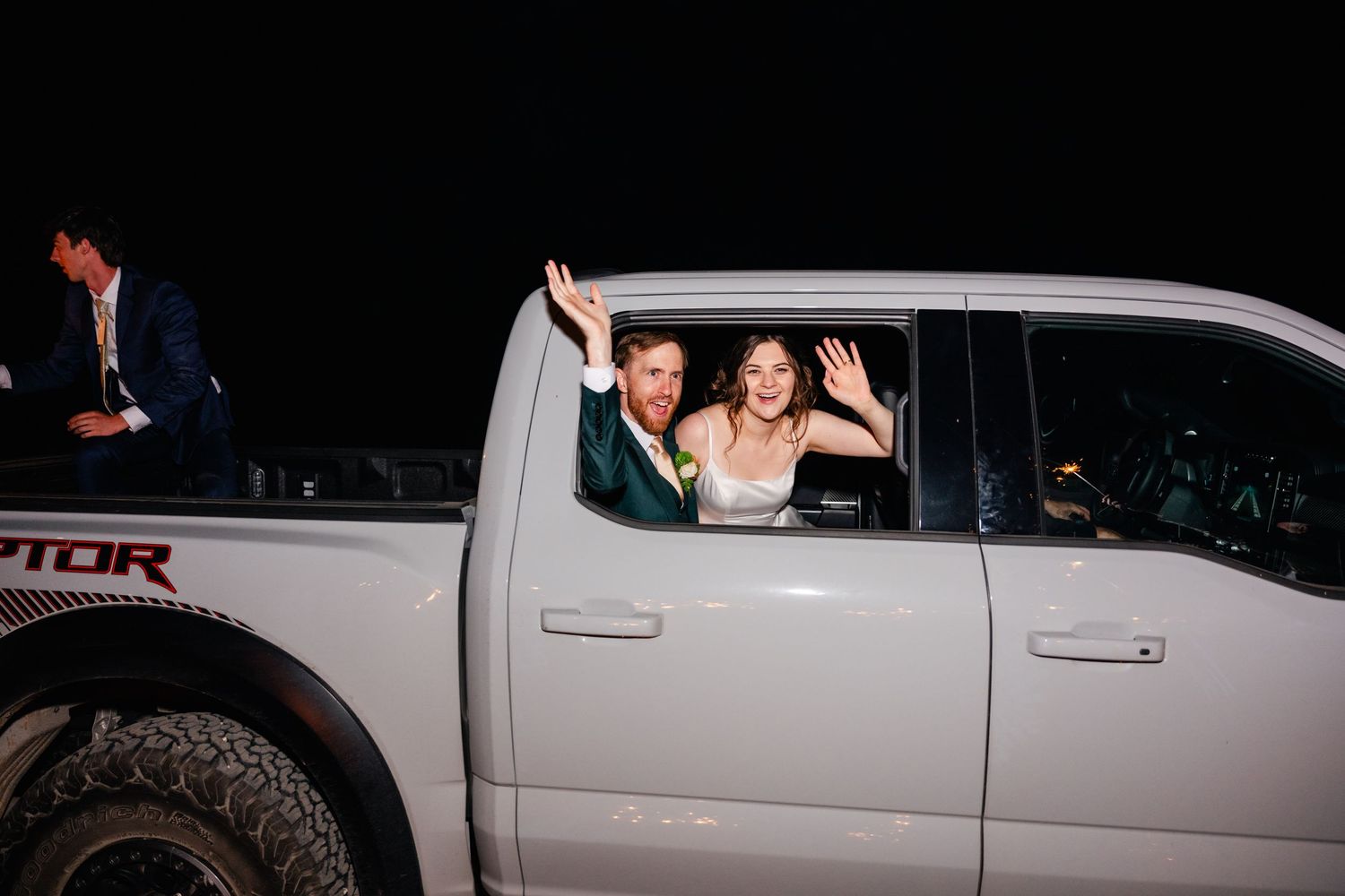 Wedding party departure in a white pickup truck decorated for the celebration.
