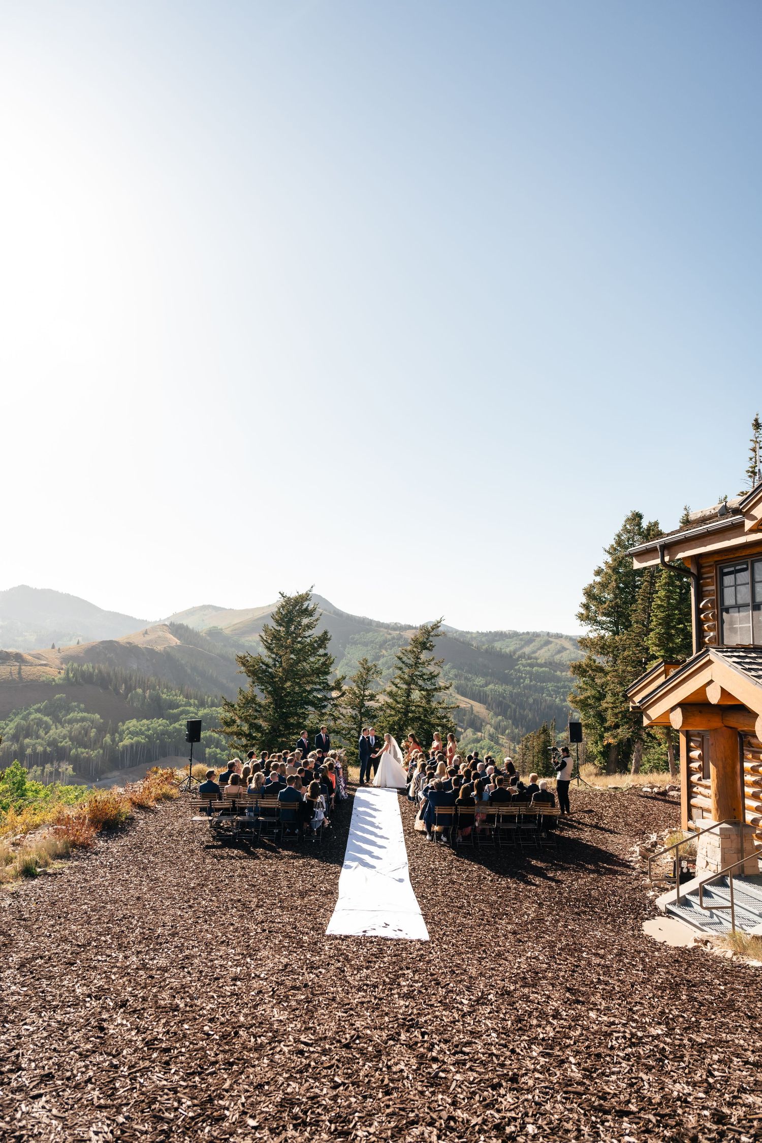 A scenic mountain wedding ceremony setup with chairs arranged on rocky terrain overlooking majestic peaks.