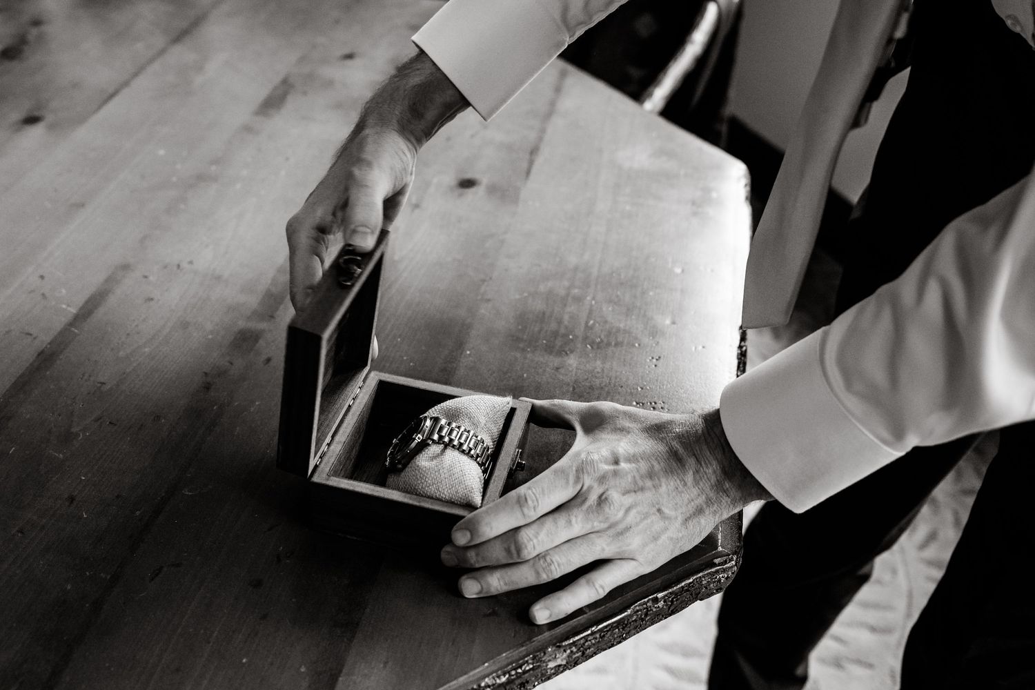 Black and white photo of hands opening a vintage photo album or book.