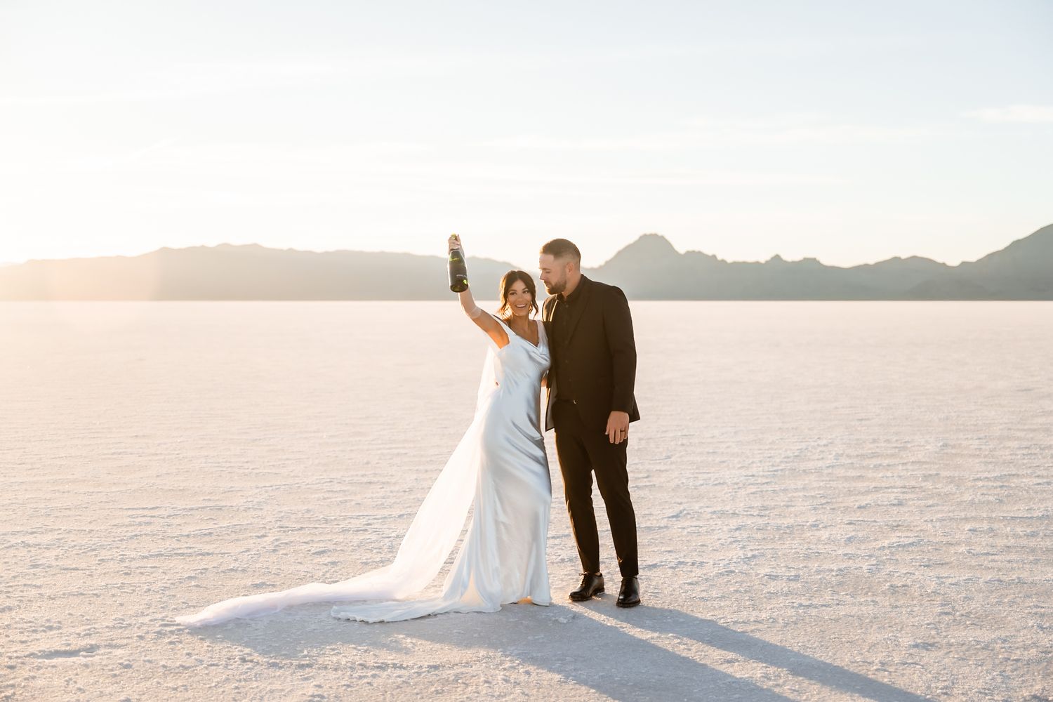 Wedding ceremony unfolds on expansive salt flats with mountain backdrop.