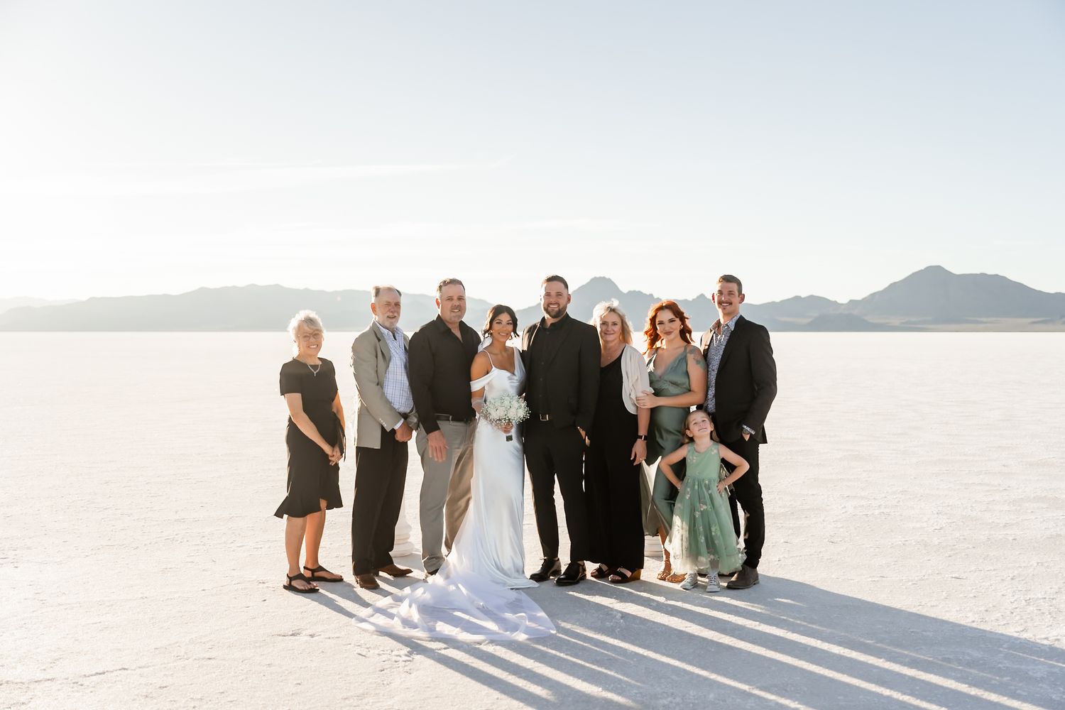 Wedding party posing together on the vast white salt flats with mountains in the distance.