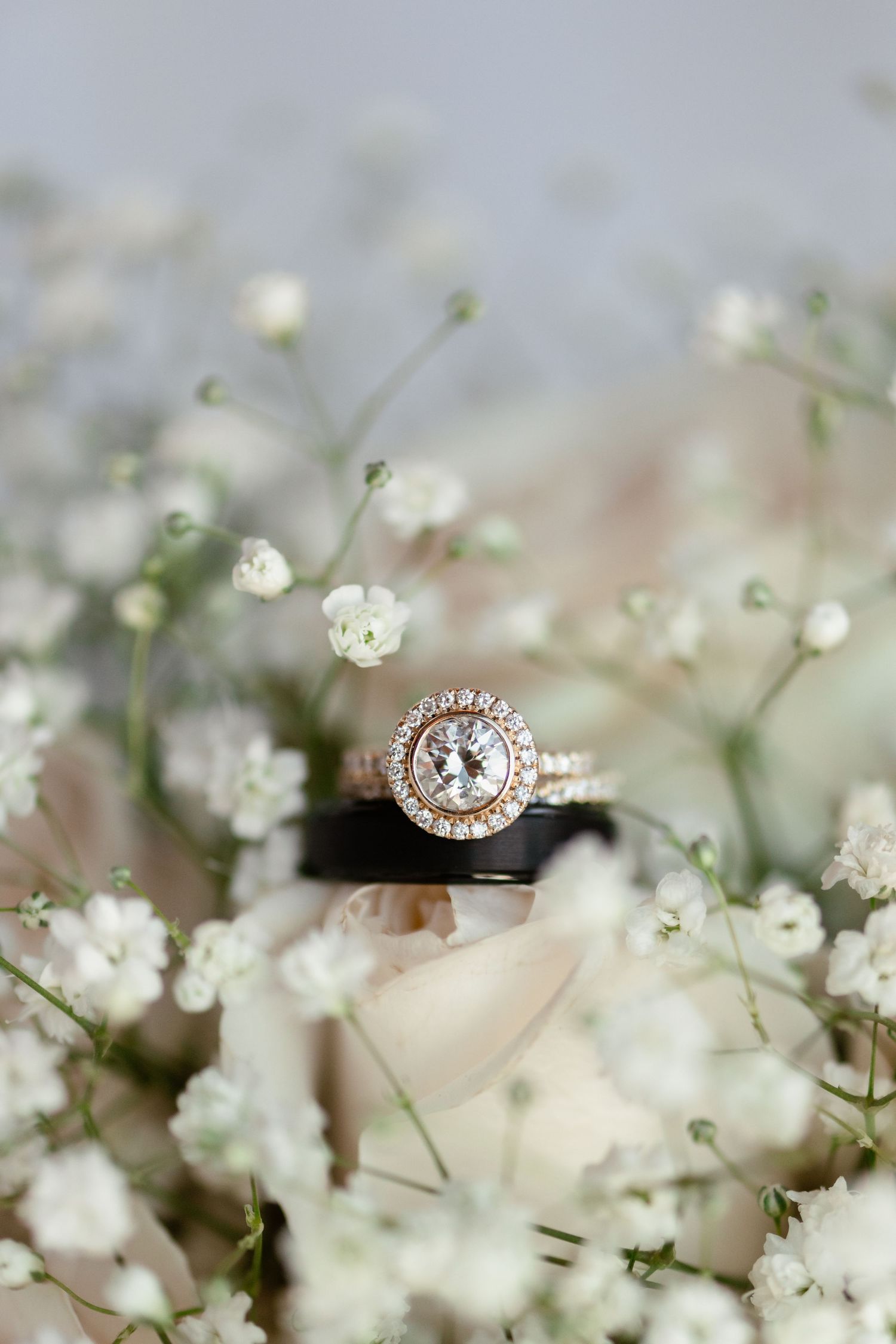 Diamond engagement ring with halo setting nestled among delicate baby's breath flowers.