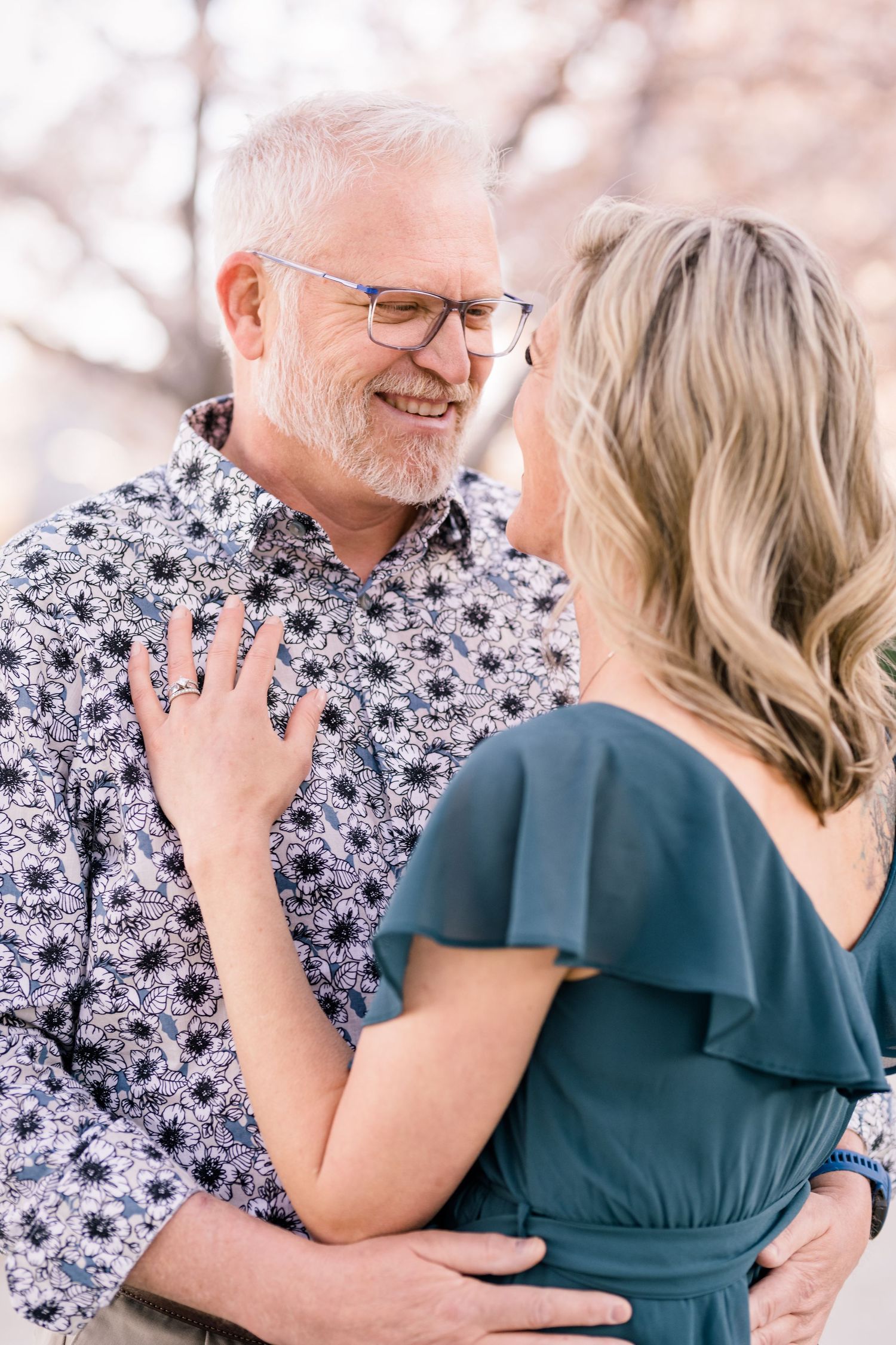Engaged couple hug warmly at the Capitol cherry blossoms by Utah wedding photographer Coley Cook