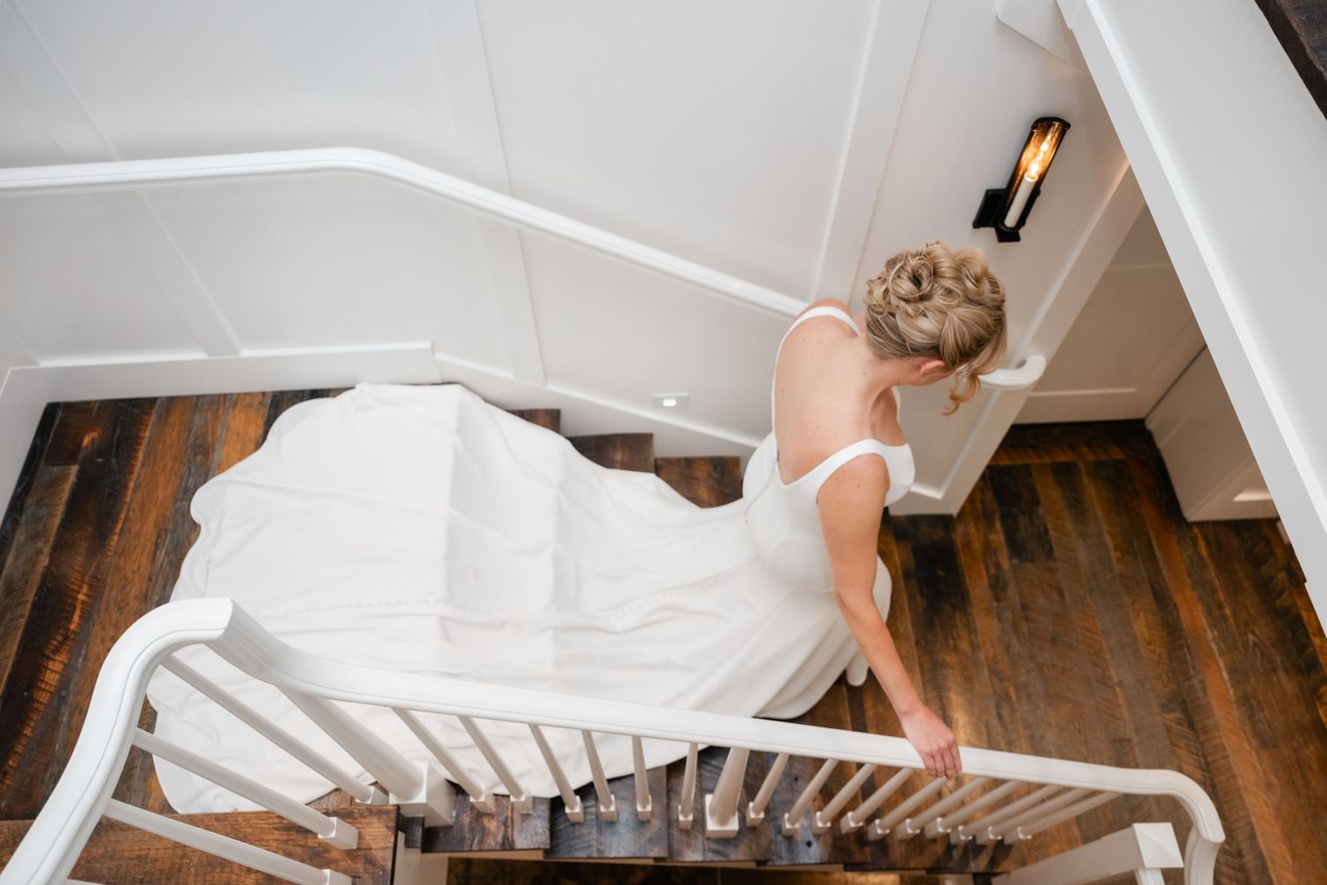 White wedding dress train cascades elegantly down wooden staircase steps.