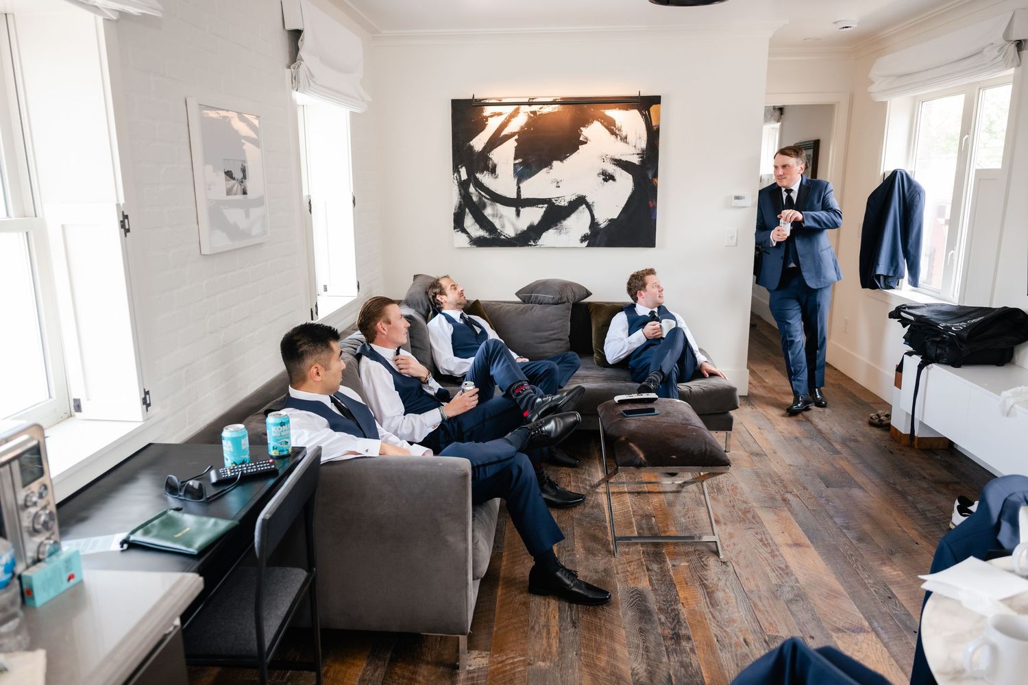 Wedding preparation room with people relaxing on furniture in natural light setting.