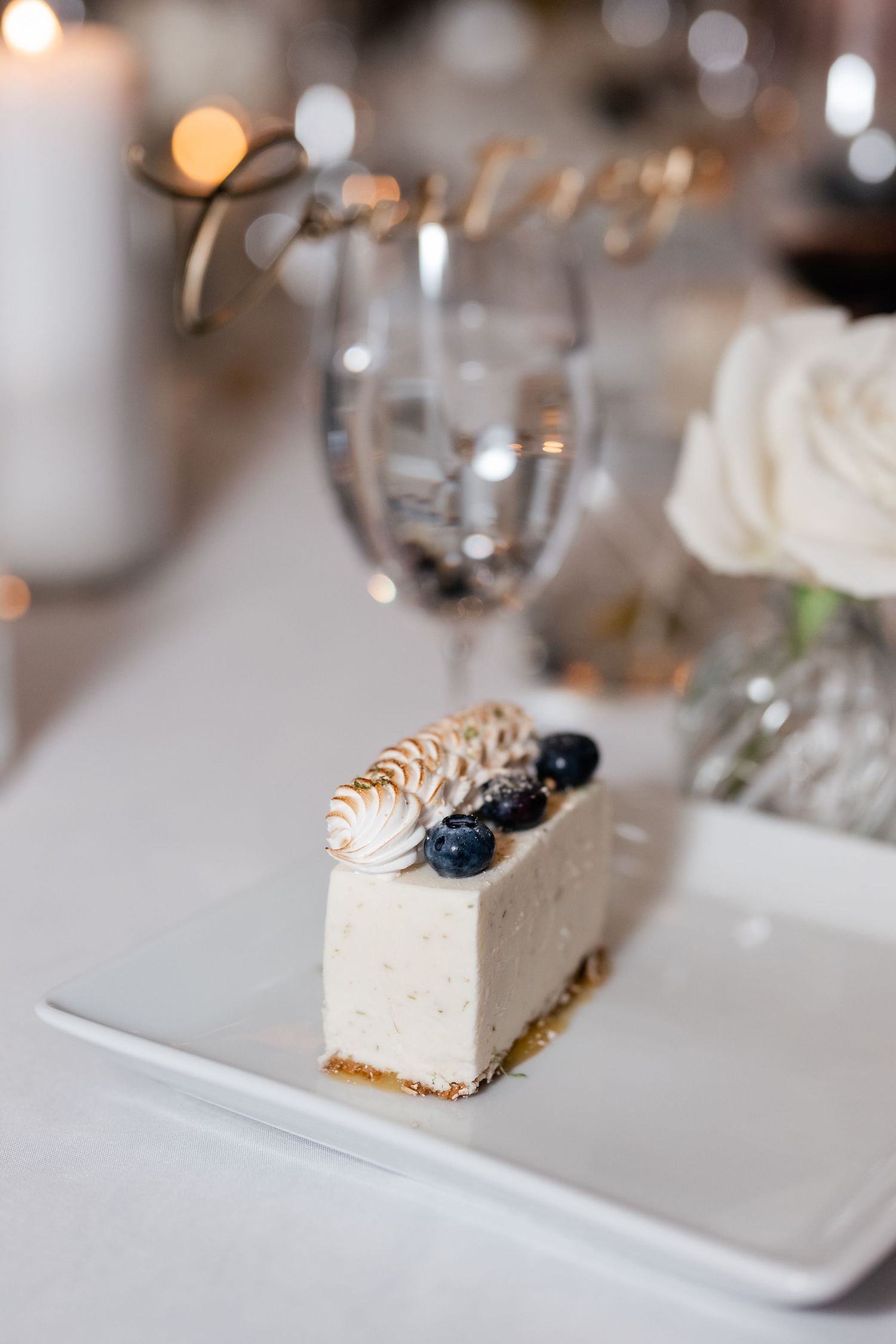 White dessert slices with blueberry garnish served on square plates.