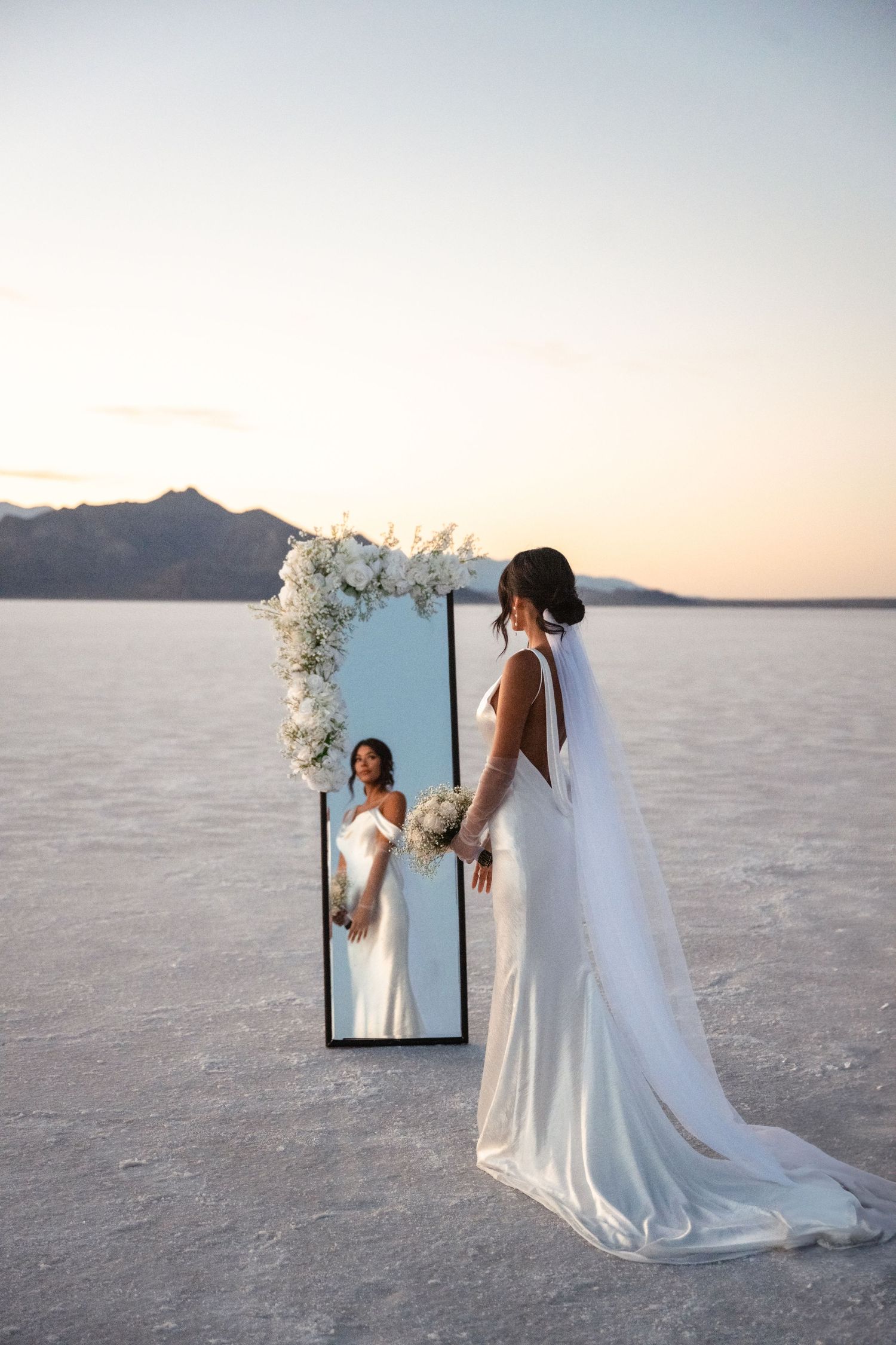 A creative wedding photo setup with mirrors reflecting bridal attire on the salt flats.