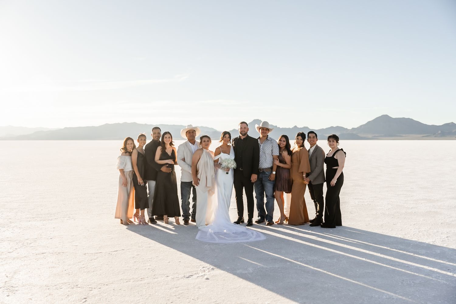 Panoramic view of wedding guests lined up on salt flats with mountains in distance.