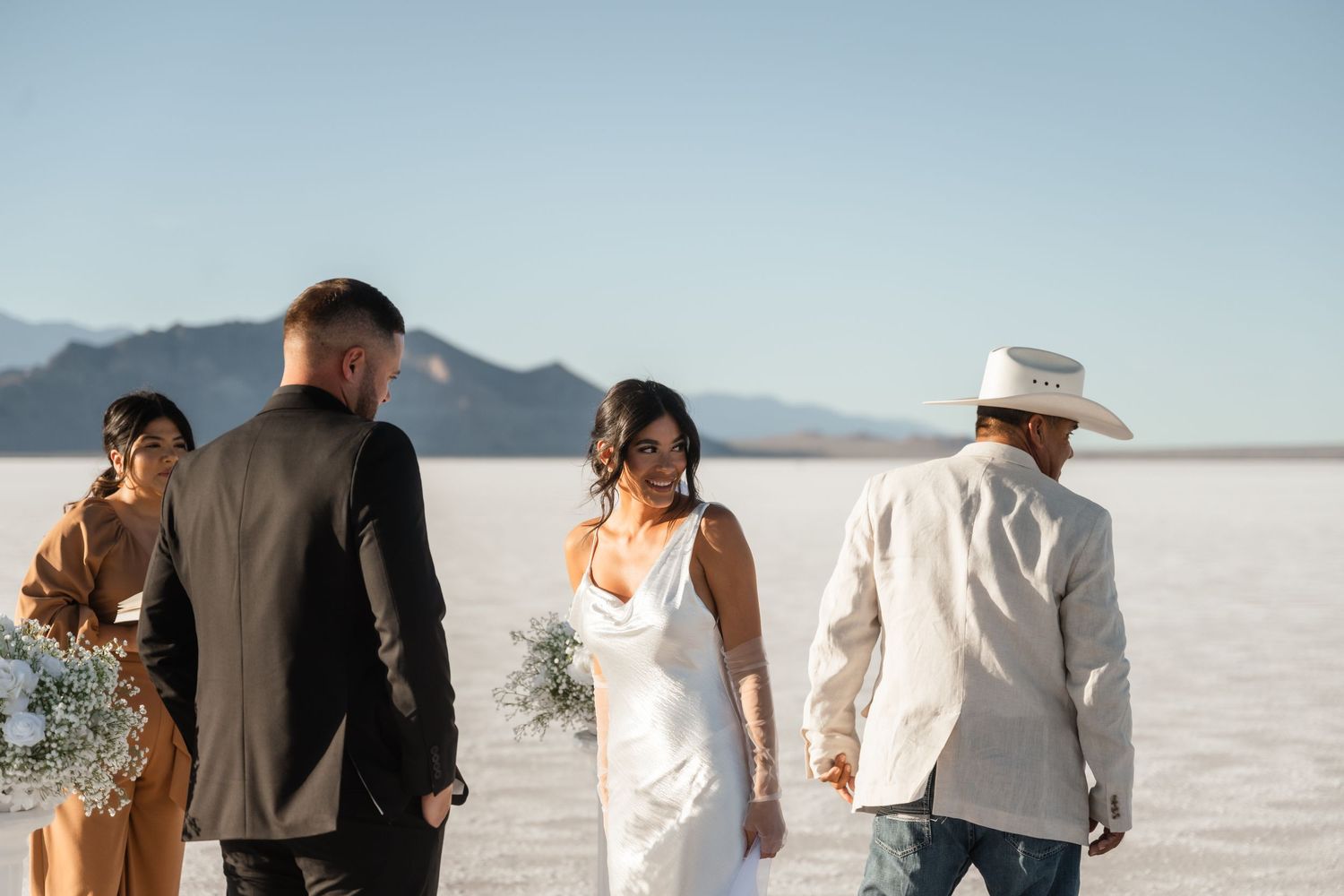 Wedding group walking across stunning salt flats with mountain backdrop.