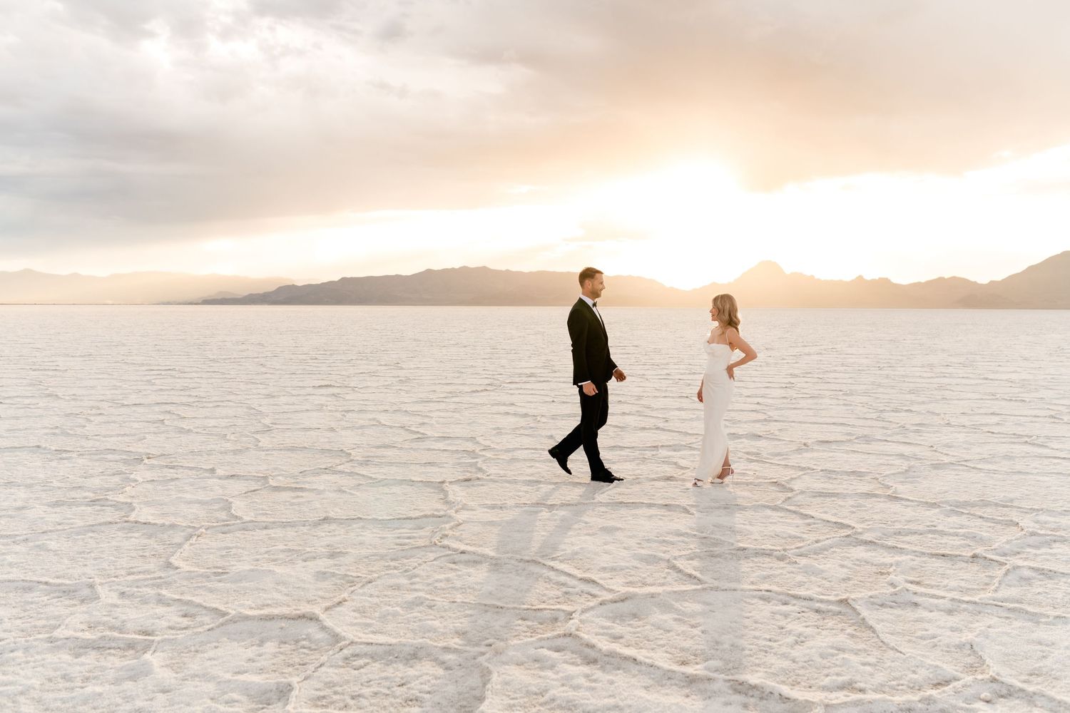 Wedding couple walking across the Bonneville Salt Flats in Utah during sunset. Utah Salt Flats Photographer.