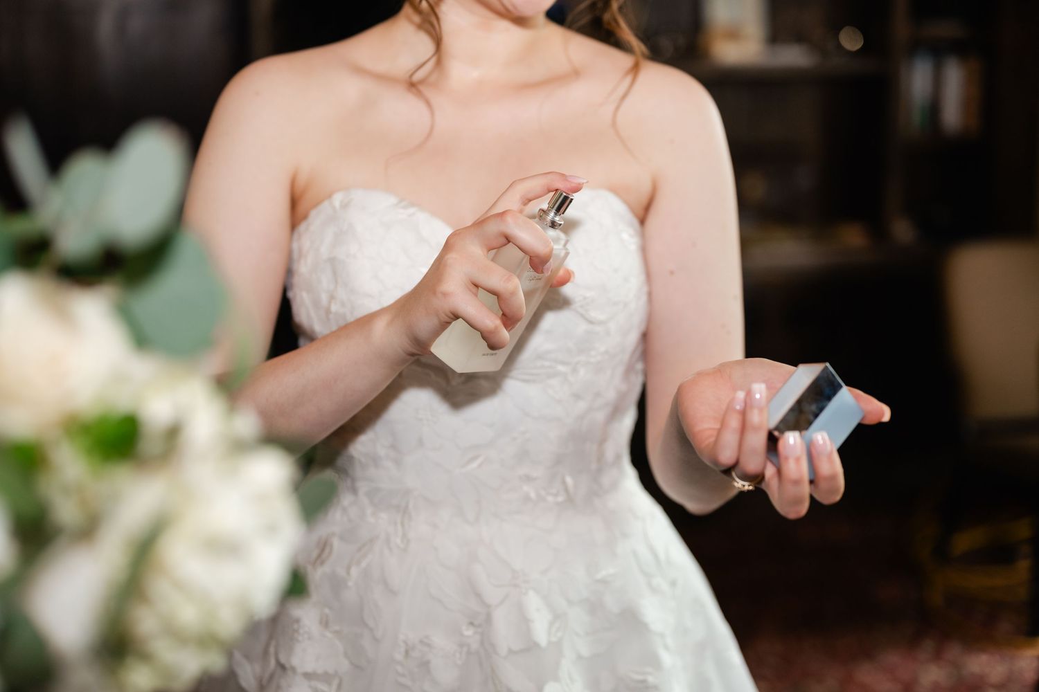 Person in white wedding dress making adjustments to clothing.