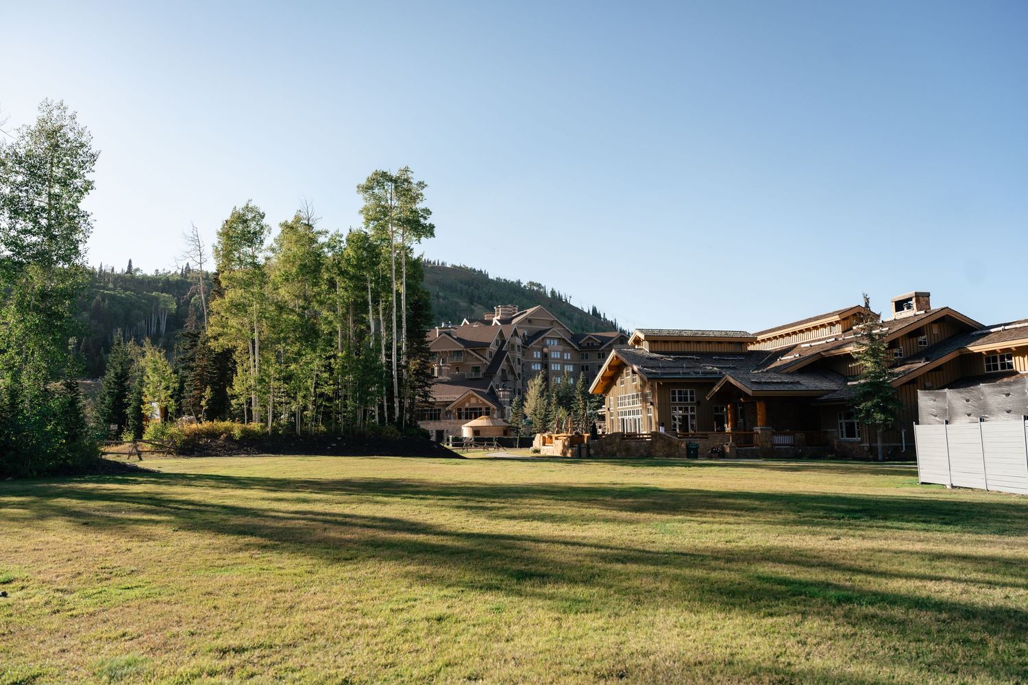 Panoramic view of a rustic mountain wedding venue with log cabins and green meadows.