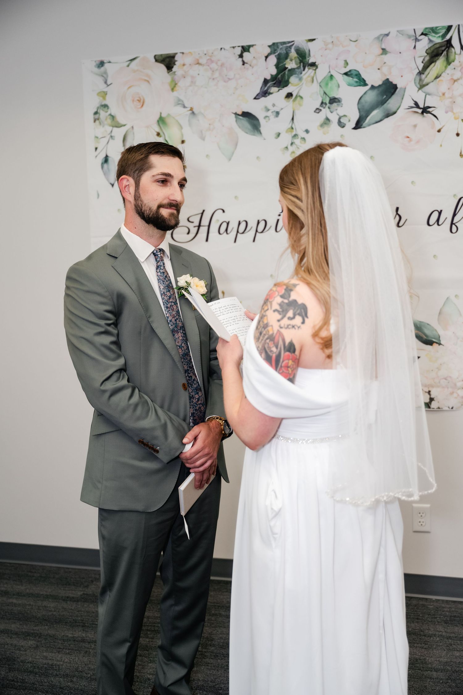 A couple shares a moment during their wedding ceremony in front of a delicate floral backdrop.