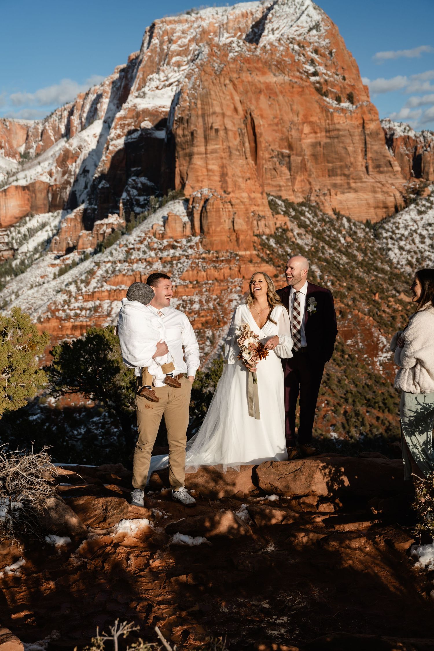 Wedding ceremony against dramatic backdrop of snow-dusted red cliffs and blue sky.