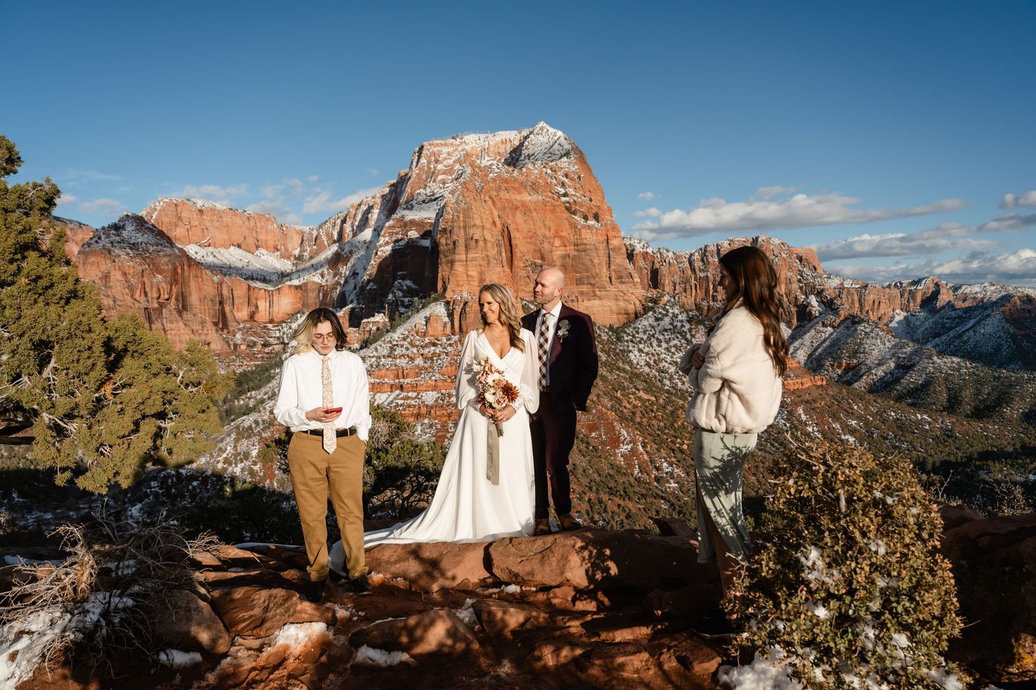 A scenic mountain ceremony overlooking majestic red rock formations dusted with winter snow.
