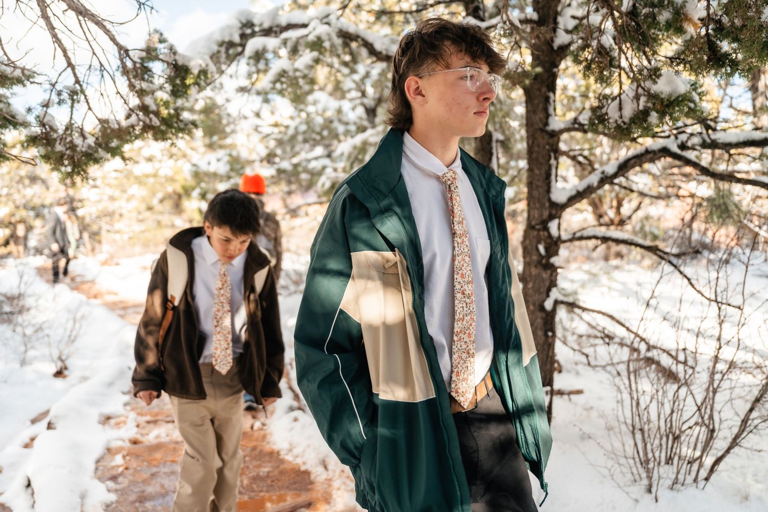 People walking along a snowy hiking trail surrounded by winter desert vegetation.