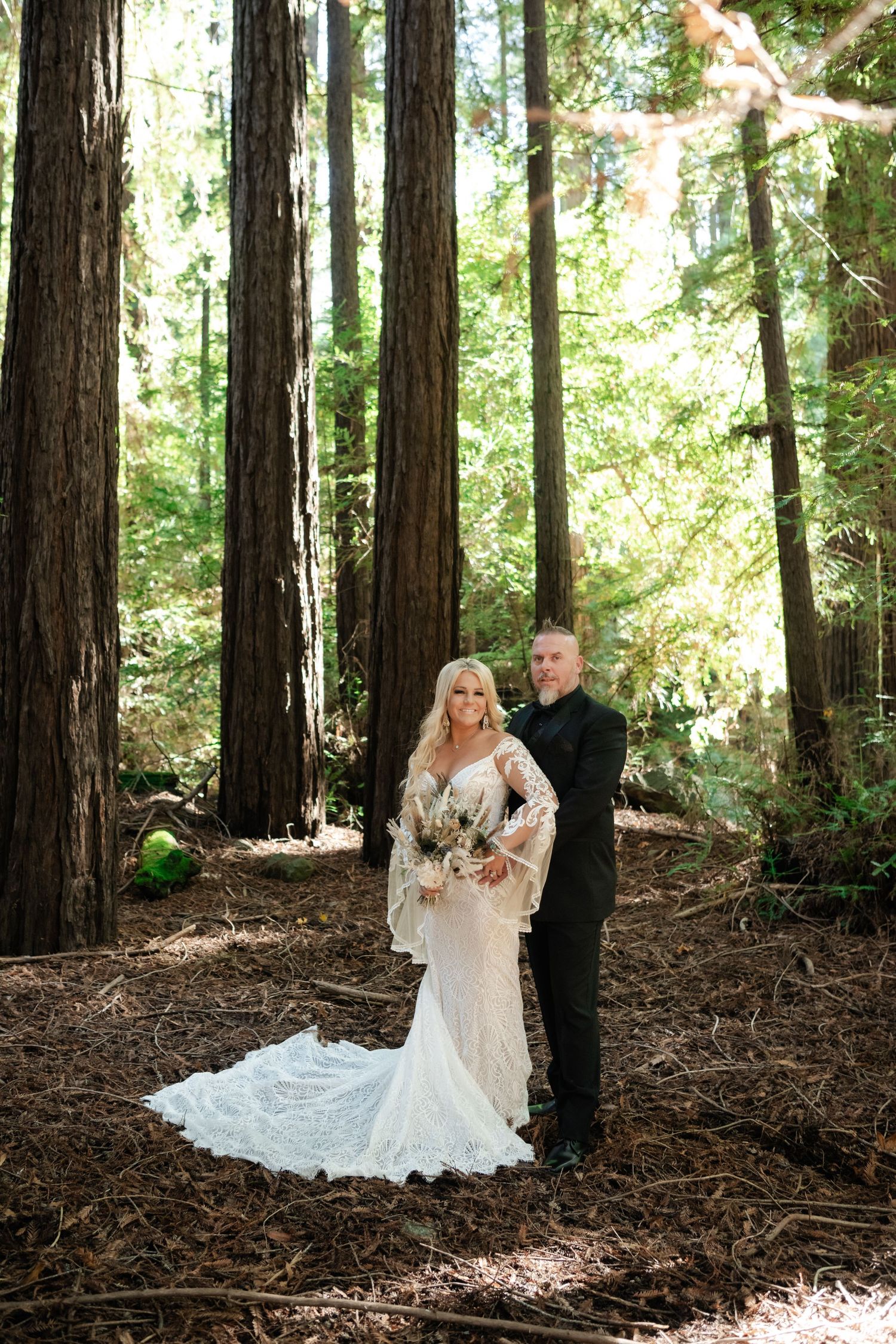 Sunlit redwood forest creates magical backdrop for wedding photos.