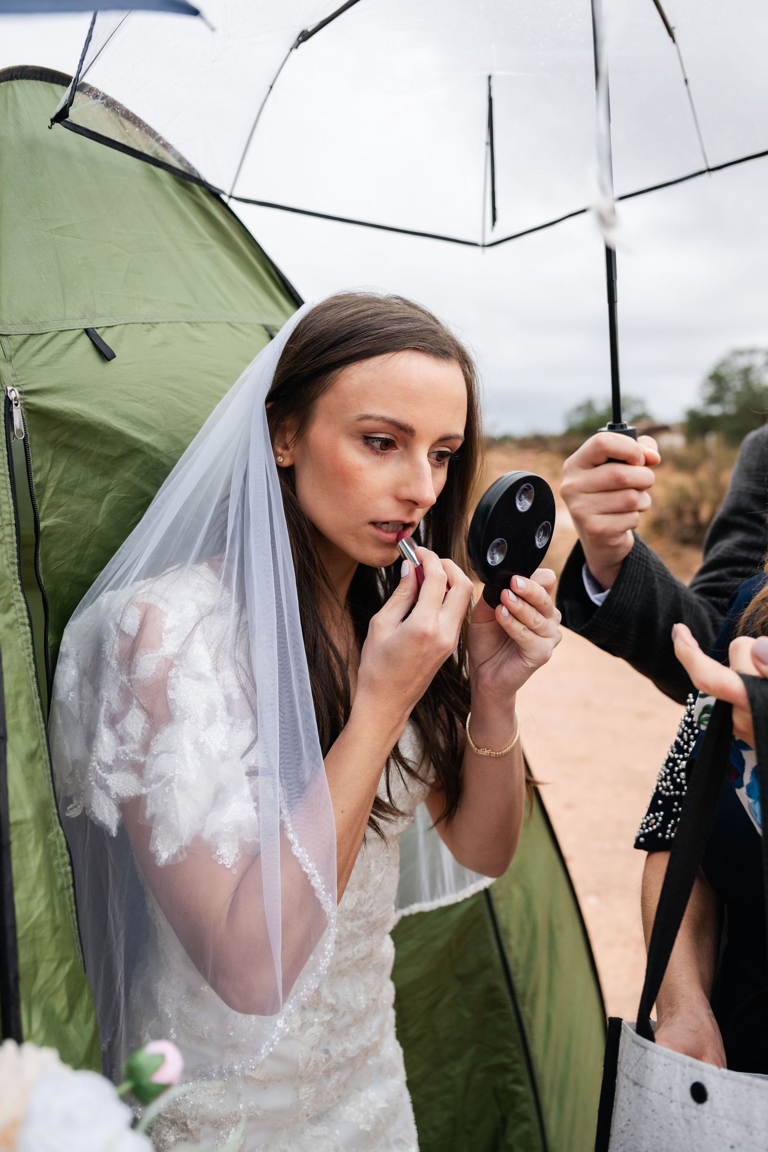 Wedding photography session under umbrellas with camera equipment visible.