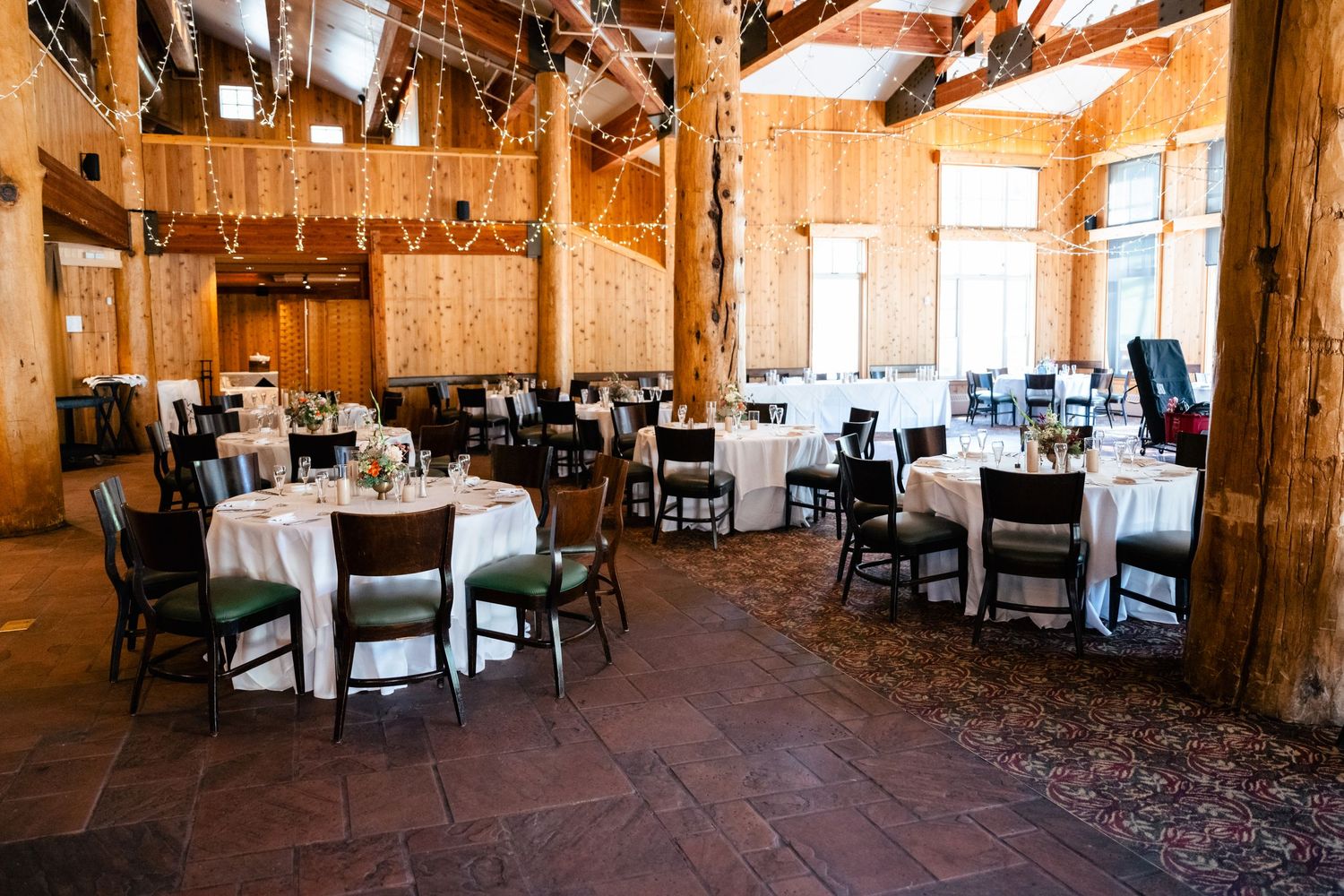 Rustic wooden lodge interior with exposed beams and elegant dining tables set for a special event.