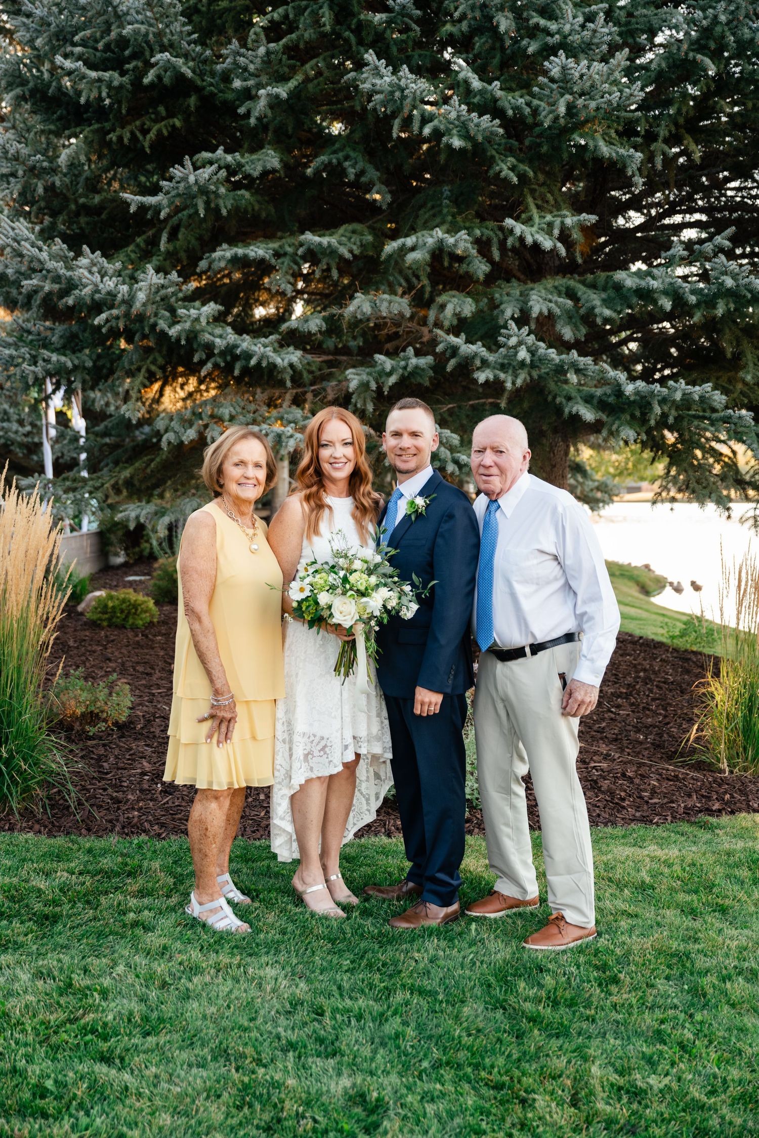 A group photo session taking place outdoors on a lawn with evergreen trees in the background.