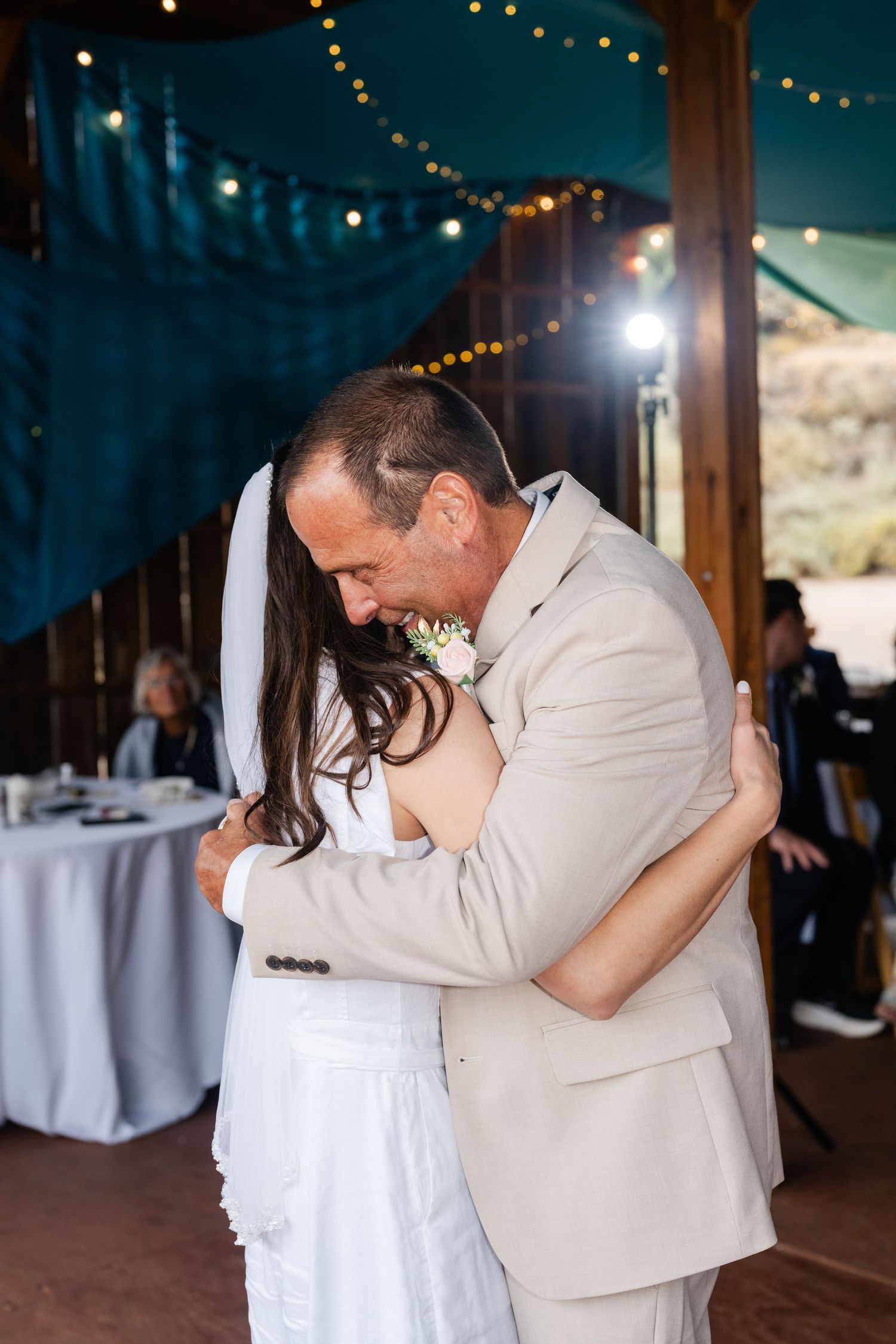 A tender dance moment captured under string lights at an outdoor wedding reception.