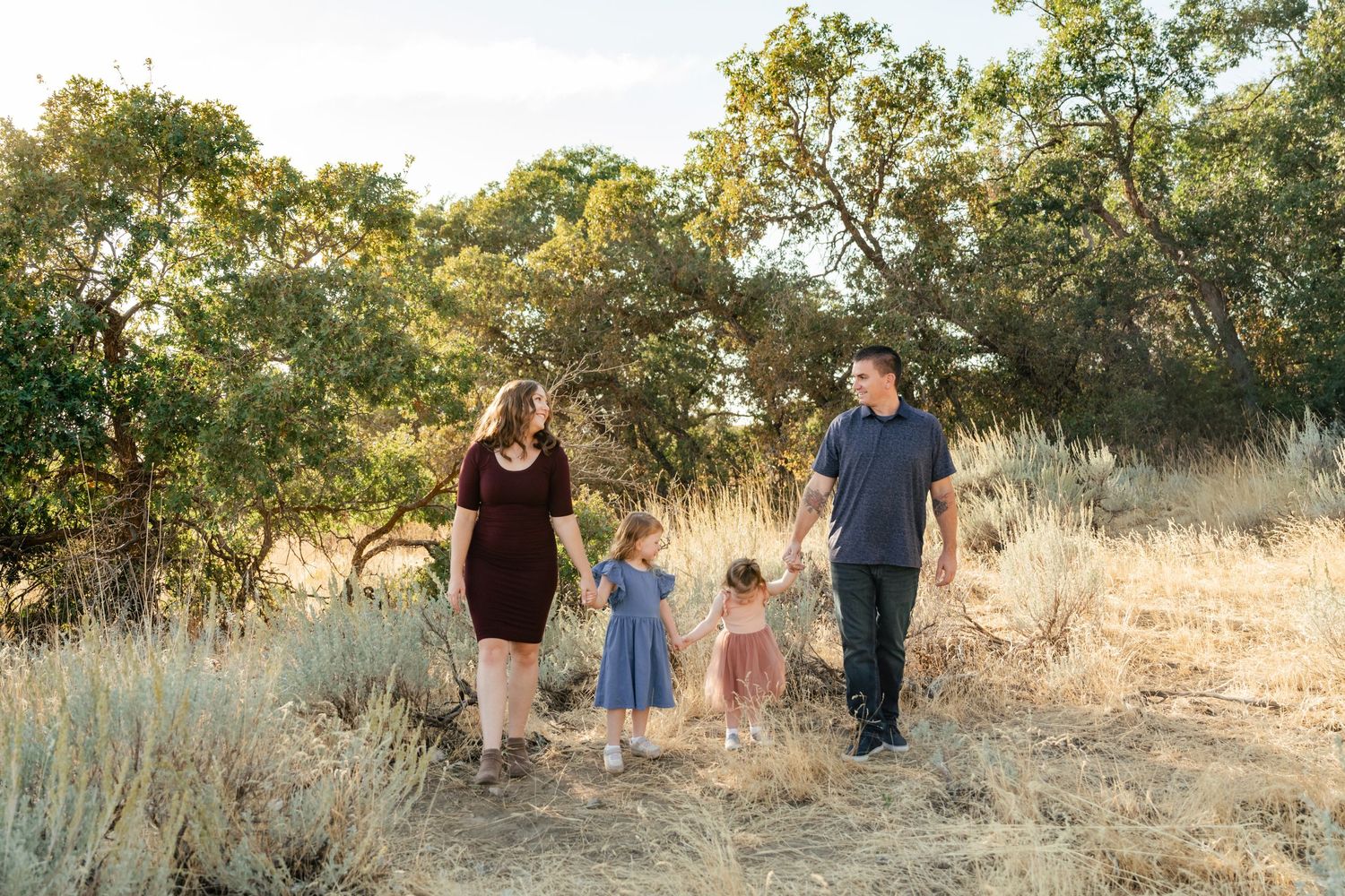Family walking together through a golden field at sunset during a photo session in nature.