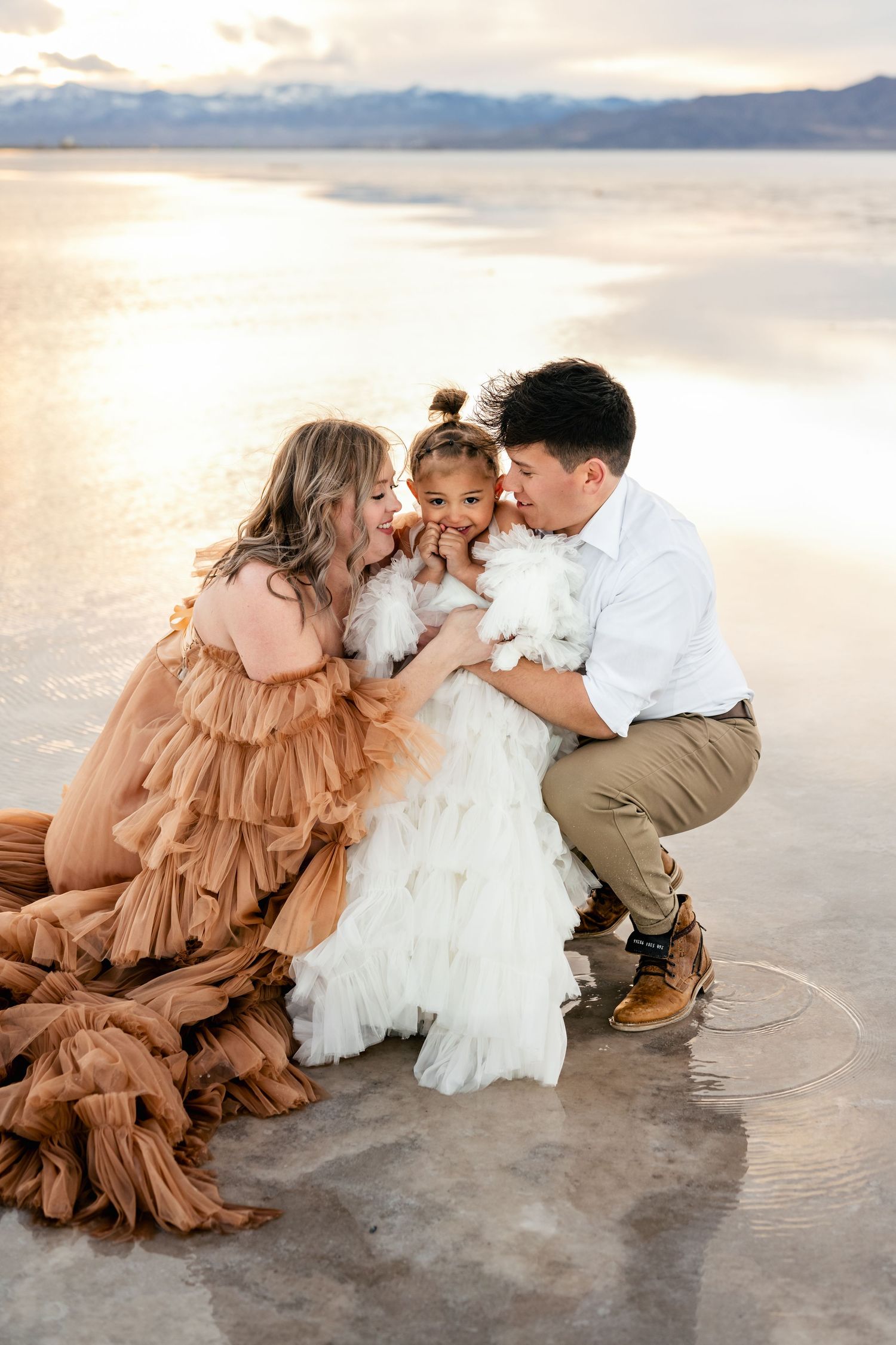Utah Salt Flats Photos. A couple shares tender moments with their small dog on the Salt Flats at sunset in matching brown and white outfits.