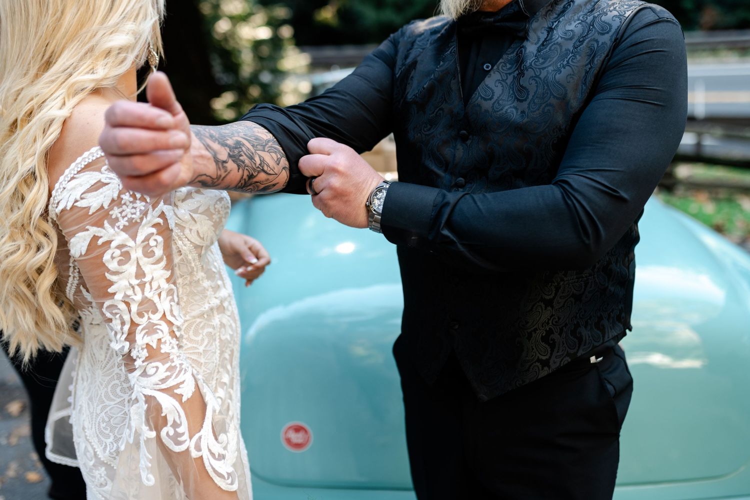 Close-up of lace dress details and formal attire against a vintage turquoise car.
