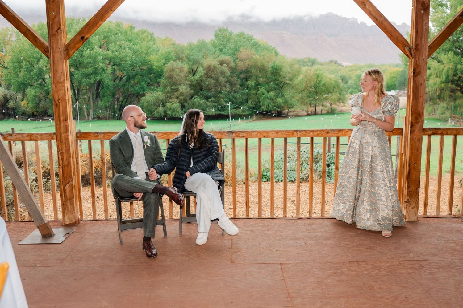 Wooden pavilion overlooking scenic countryside with guests mingling on the deck.