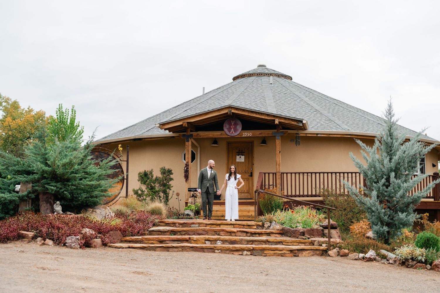 Exterior view of rustic desert wedding venue buildings with native landscaping and mountain backdrop.