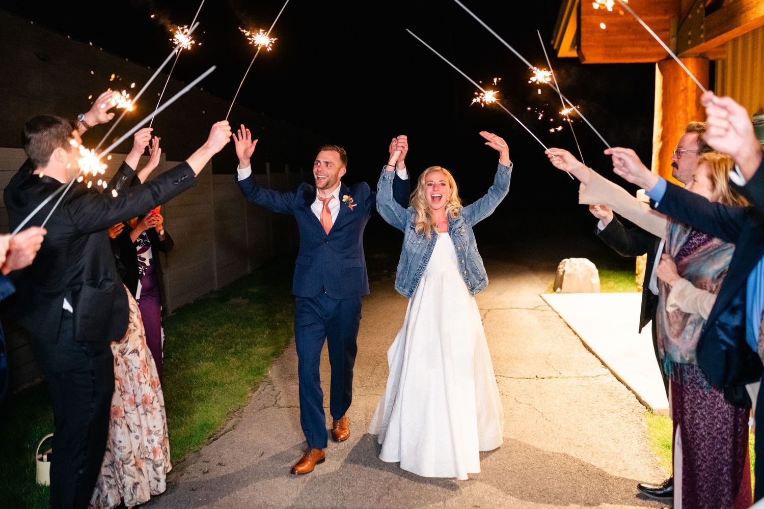 Wedding guests celebrating with sparklers during nighttime sendoff.