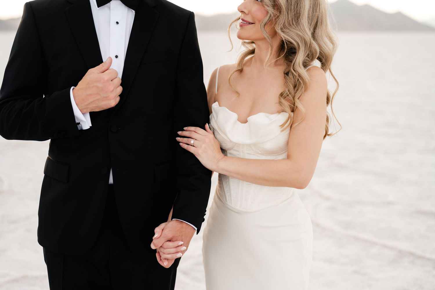 Salt Flats Elopement Photographer. A couple in formal attire shares an intimate moment on the salt flats with mountains in the background.