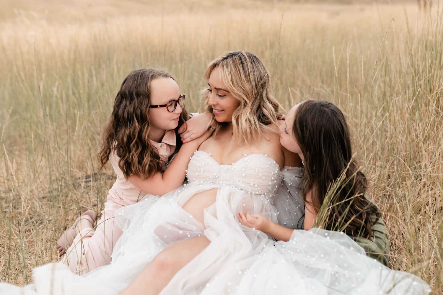 A group embraces in a golden wheat field during sunset creating a warm and intimate family moment.