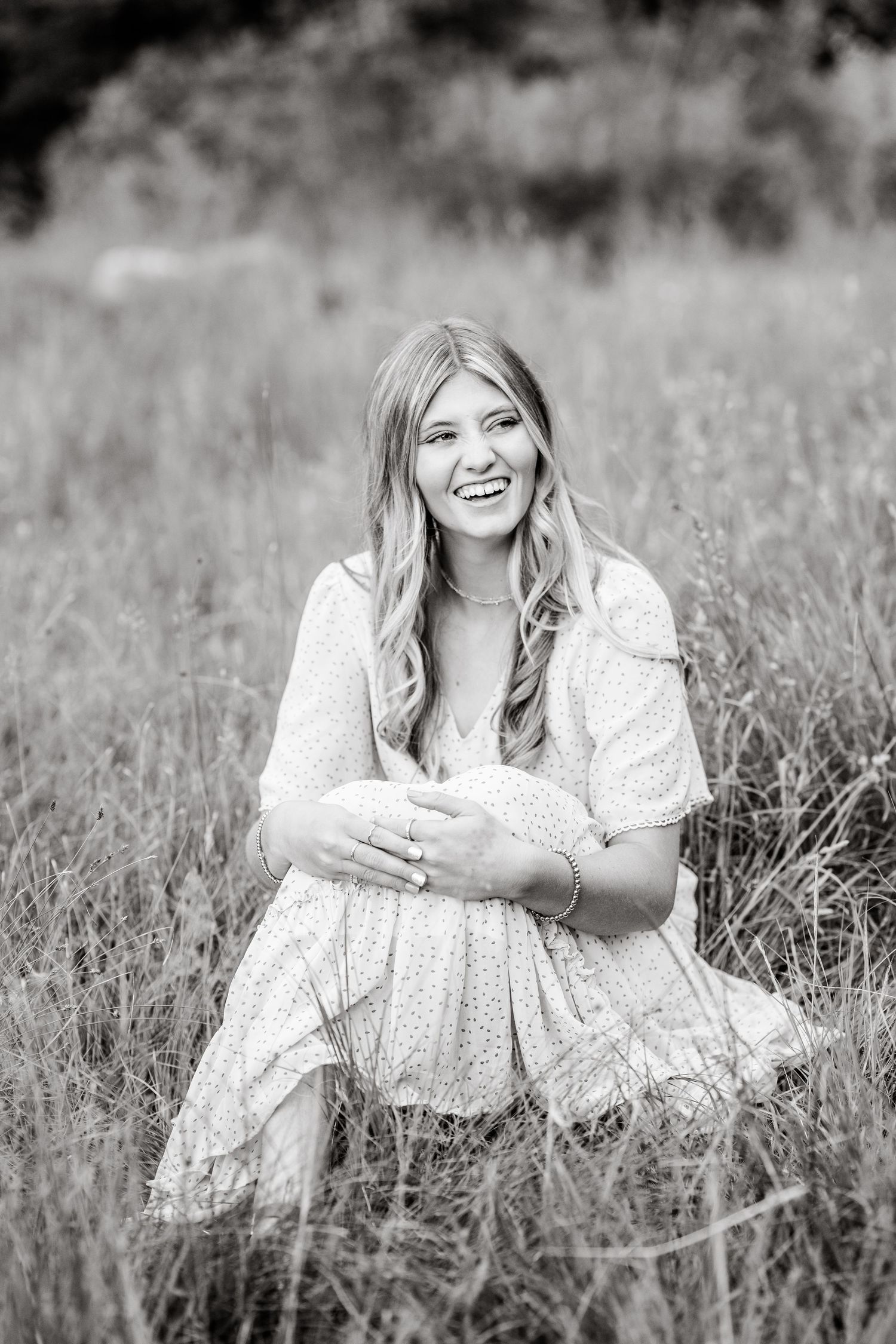 Black and white portrait series showing a person in a polka dot dress lying in a wildflower meadow.