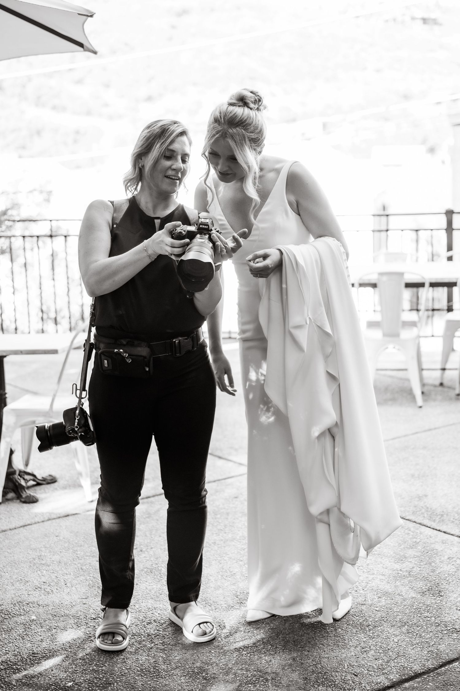 Black and white candid wedding preparation moment on outdoor patio.