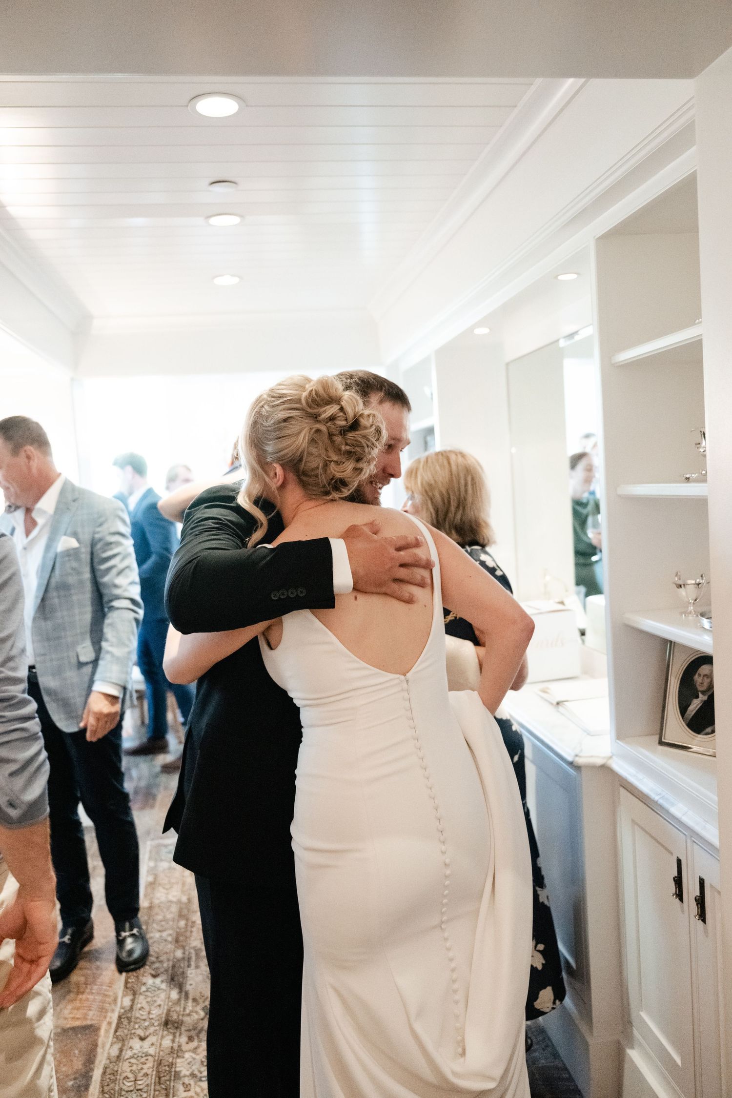 Intimate wedding moments captured in a bright hallway with white paneled walls.