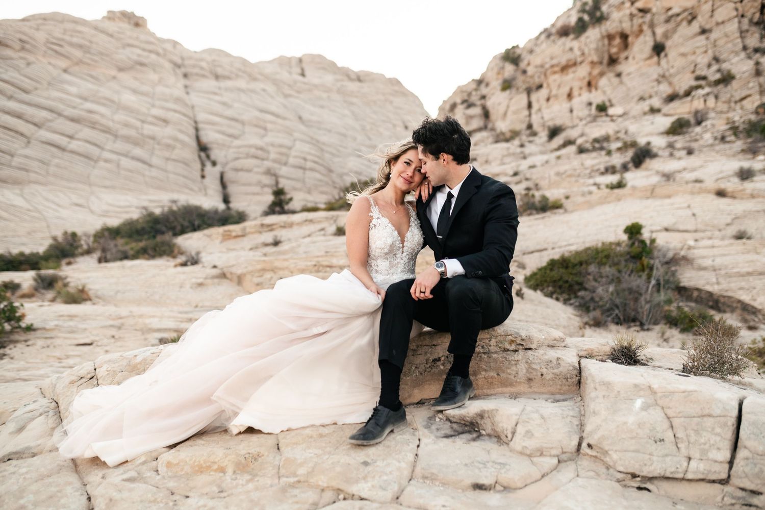 A romantic couple shares intimate moments against stunning desert rock formations during their wedding photoshoot. Snow Canyon Wedding.