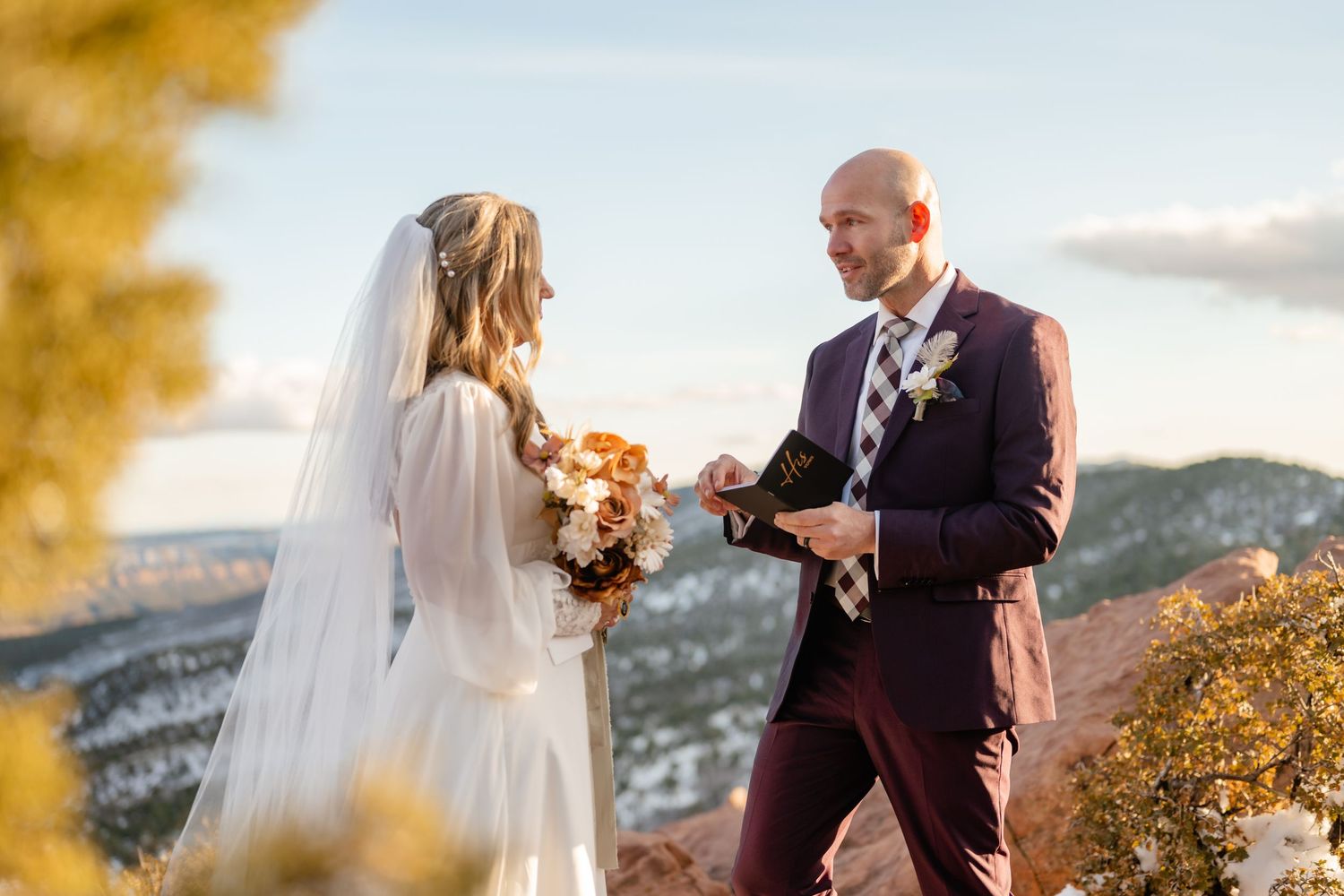 A couple exchanges vows during their sunset mountain wedding ceremony.