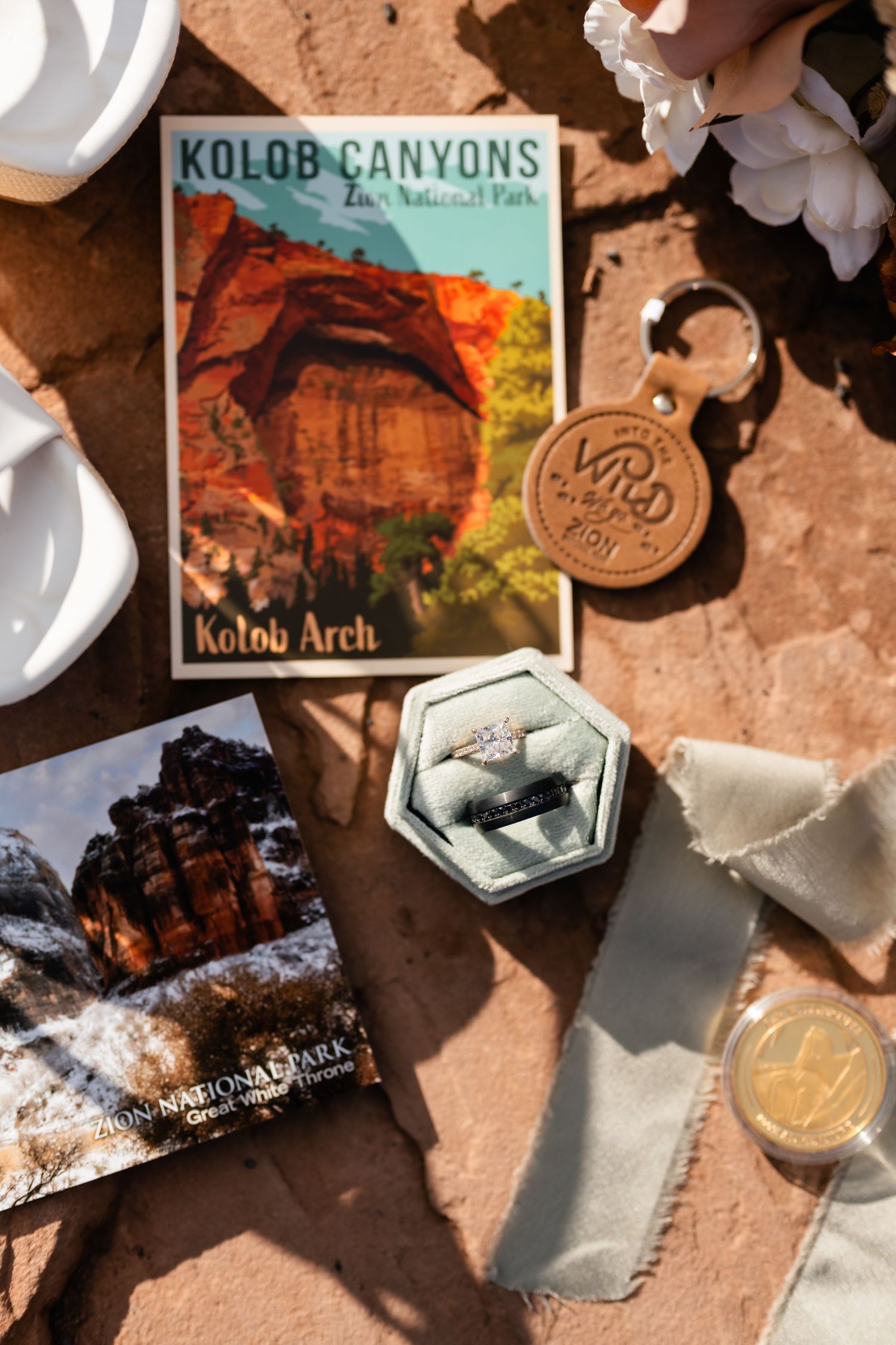 Collection of Kolob Canyons park memorabilia and coins scattered on a red rock surface.