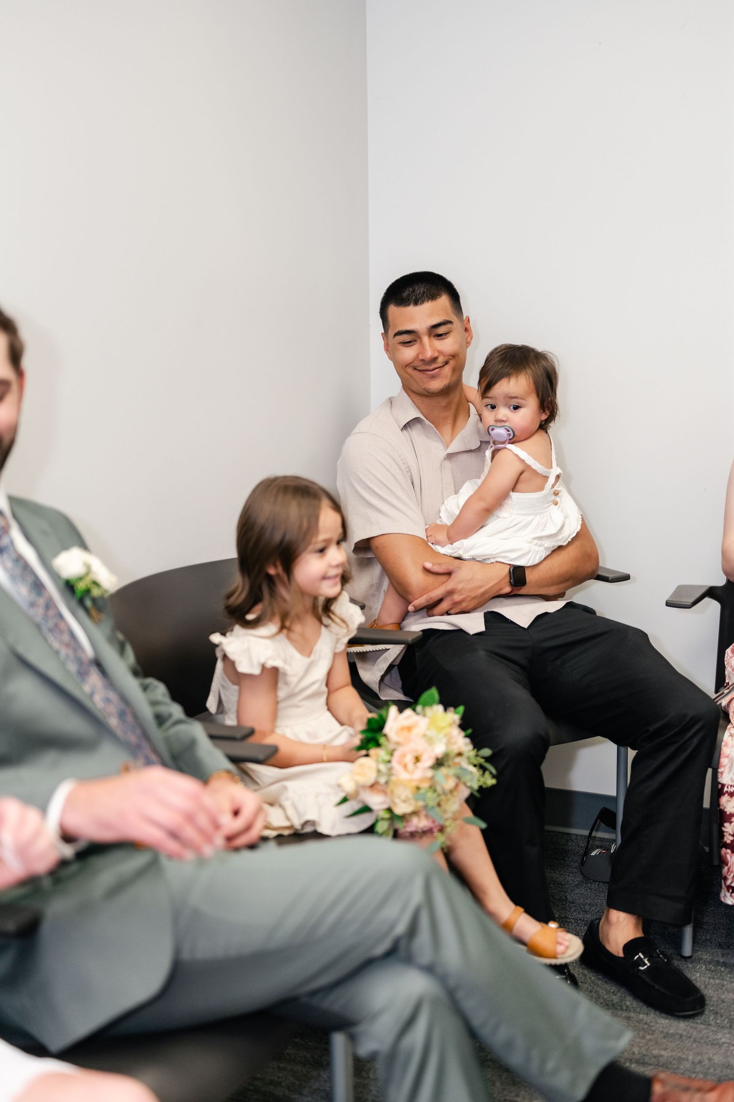 Wedding guests sitting in chairs during an indoor ceremony.