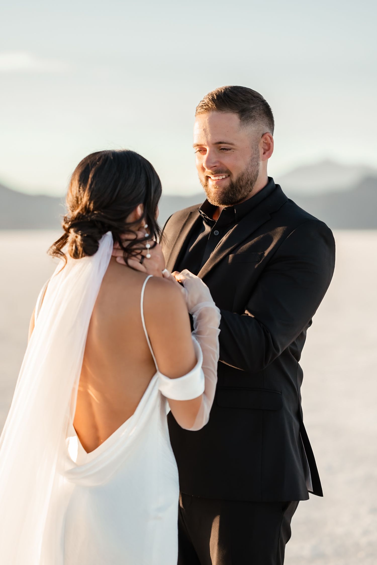 A couple shares an intimate moment during their wedding photoshoot on salt flats at sunset.