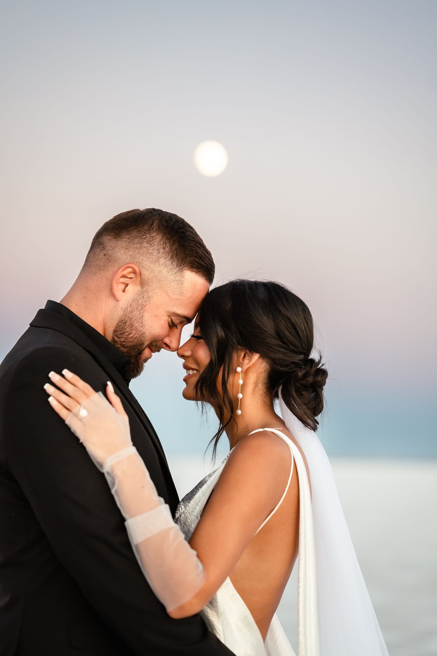Intimate wedding couple portraits at sunset on salt flats with soft pink sky.