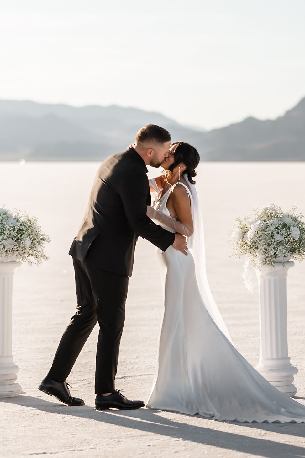 Wedding ceremony setup with white columns on salt flats during golden hour.
