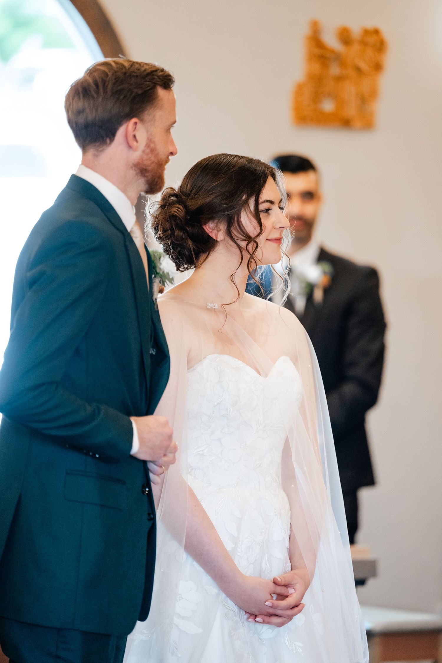 Intimate wedding moment captured in a bright indoor setting with formal attire.